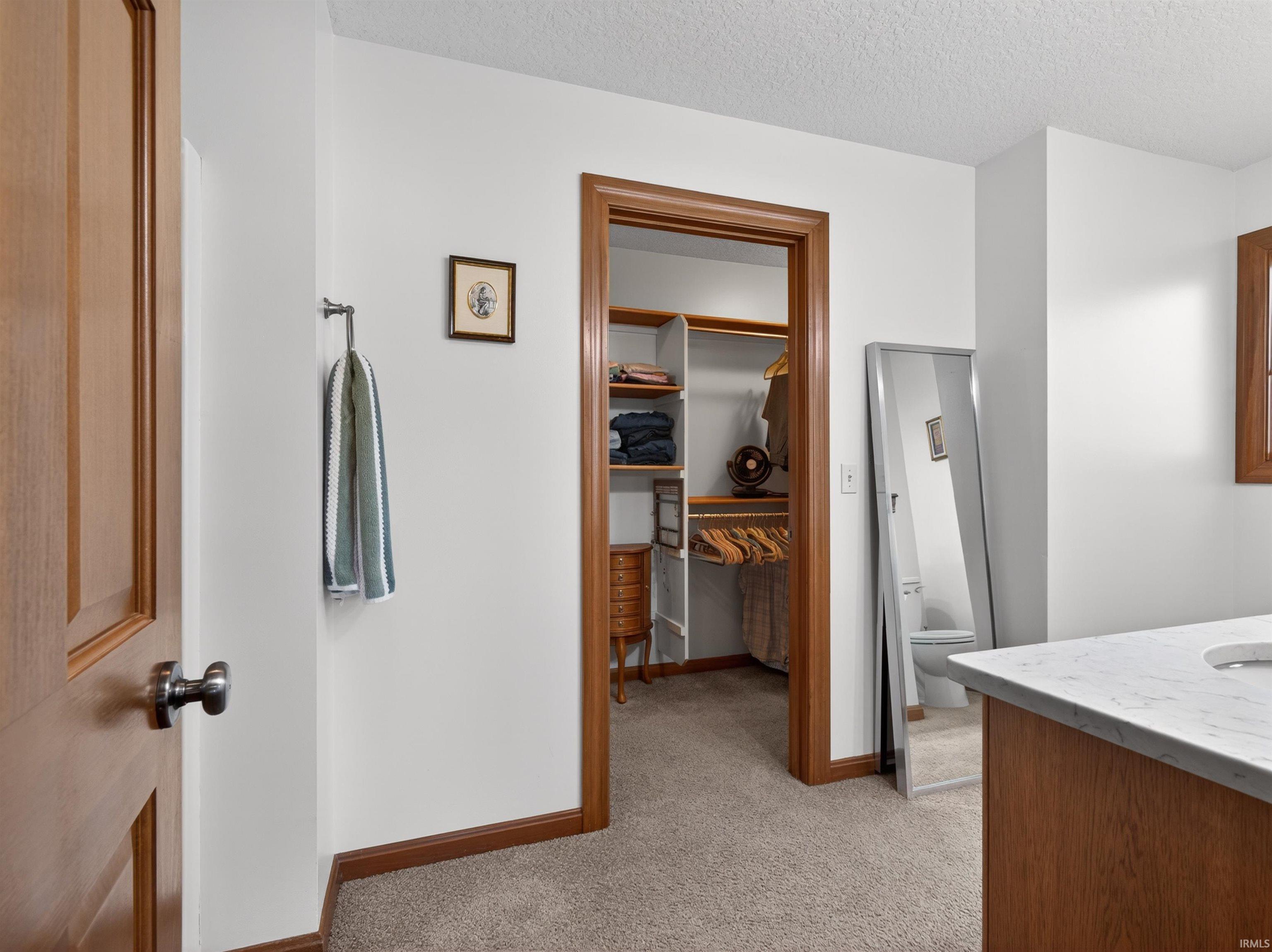 Walk-in closet featuring wood-finish shelving and hanging rods