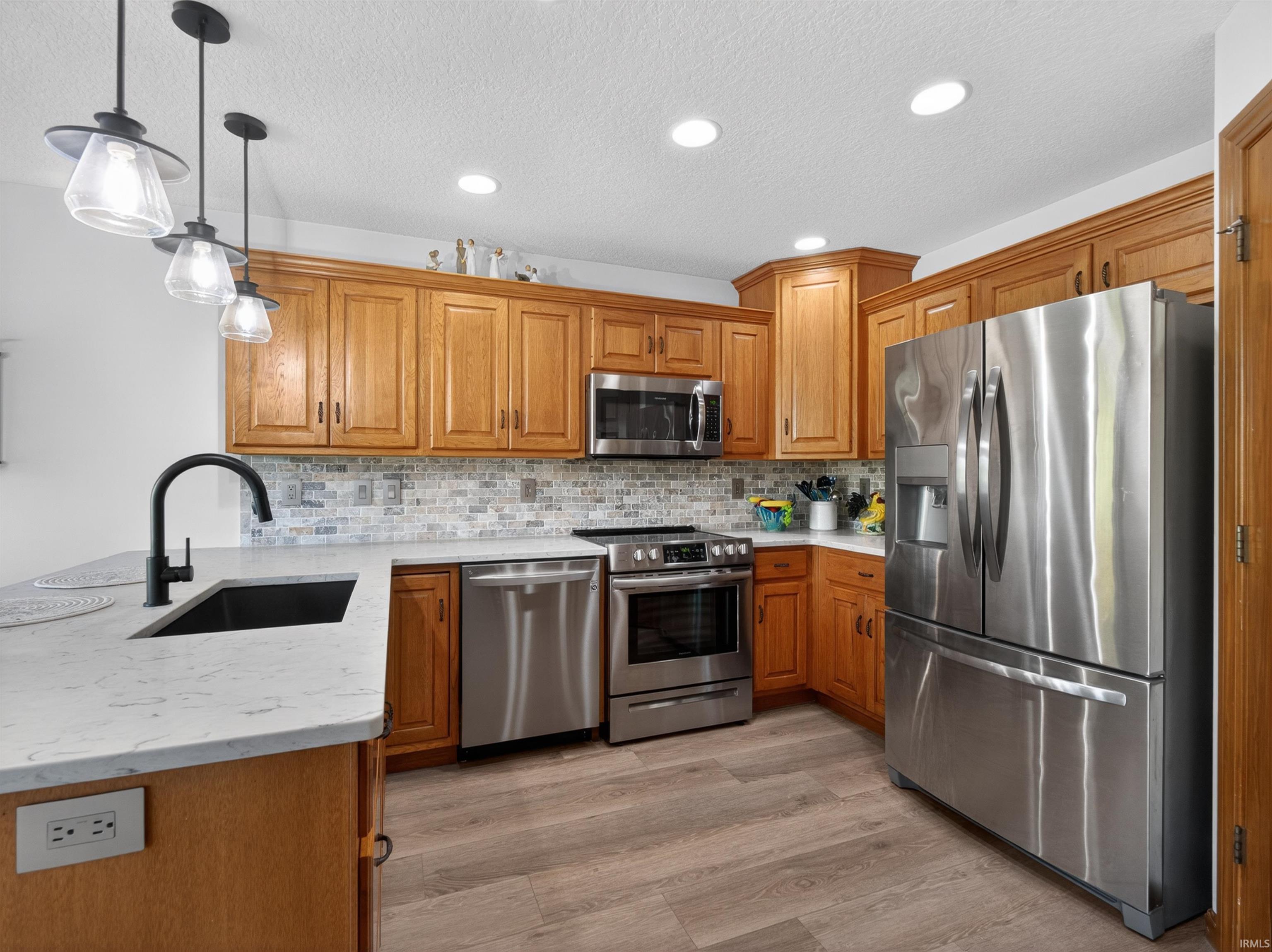 Kitchen featuring CUSTOM STAINED GRABILL cabinetry, QUARTZ countertops, TILE BACKSPLASH, 3 TIER DISHWASHER HIDDEN PANEL AND STAINLESS STEEL INTERIOR, DOULBE DOOR WITH ICE AND WATER, AND BOTTOM FREEZER, MICROWAVE TO MATCH. QUARTZ SINGLE BOWL SINK.
