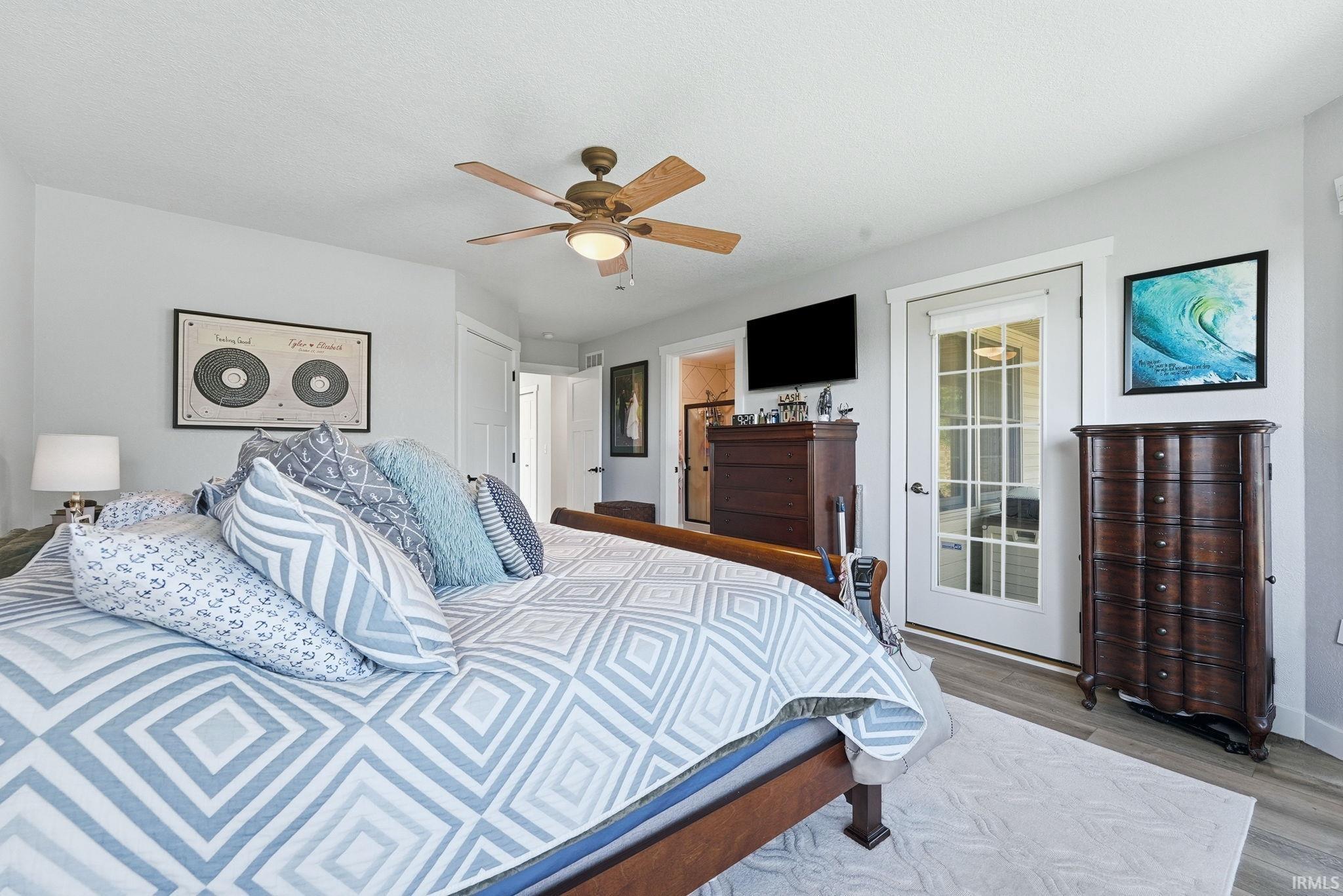 Spacious room featuring wood-finish flooring, light grey wall paint, and a ceiling fan with integrated lighting