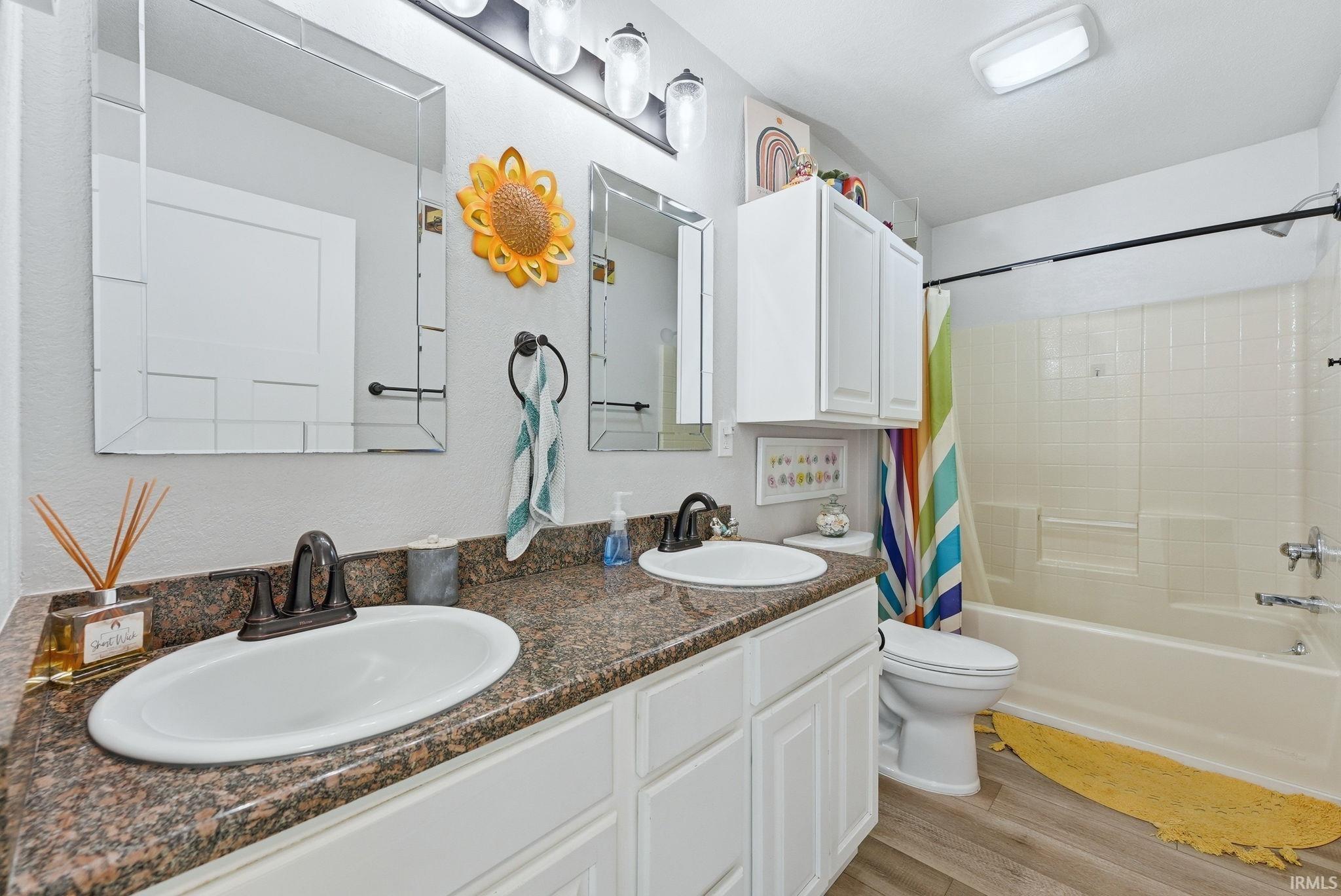 Bathroom featuring a dual vanity with undermount sinks, a brown speckled countertop, white cabinetry, rectangular mirrors with mirrored frames, and a tub-shower combination with white subway tile surround
