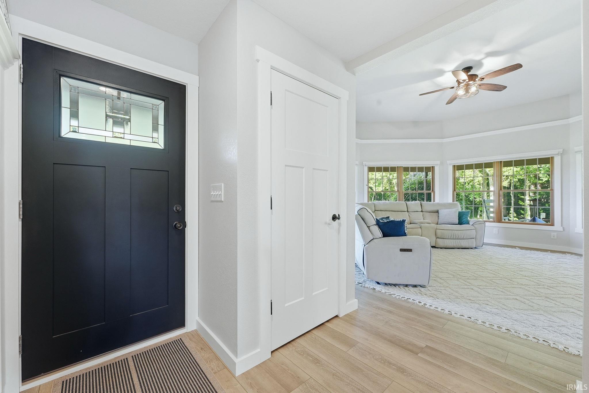 Entryway featuring a black paneled door with leaded glass, light wood-finish flooring, and white trim