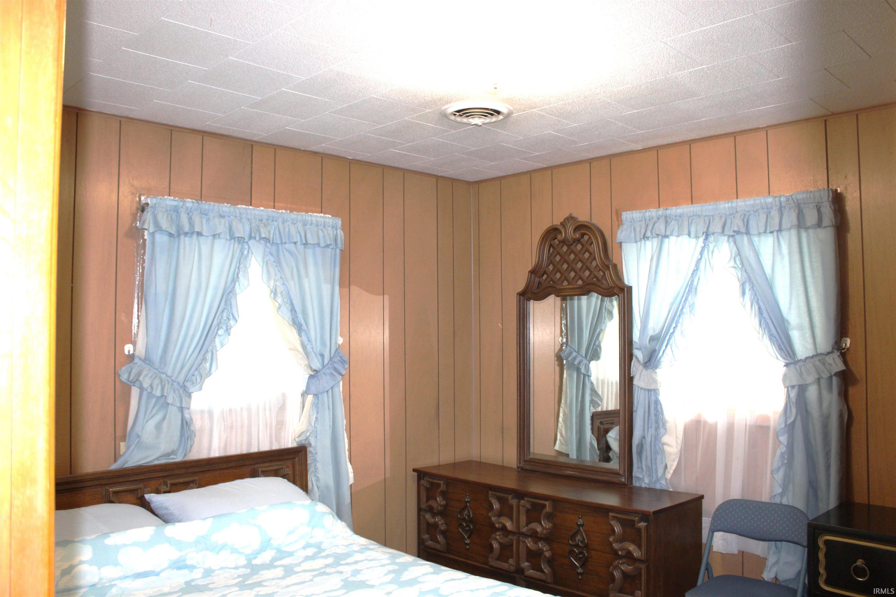 Wood-paneled walls featuring a window with light blue curtains