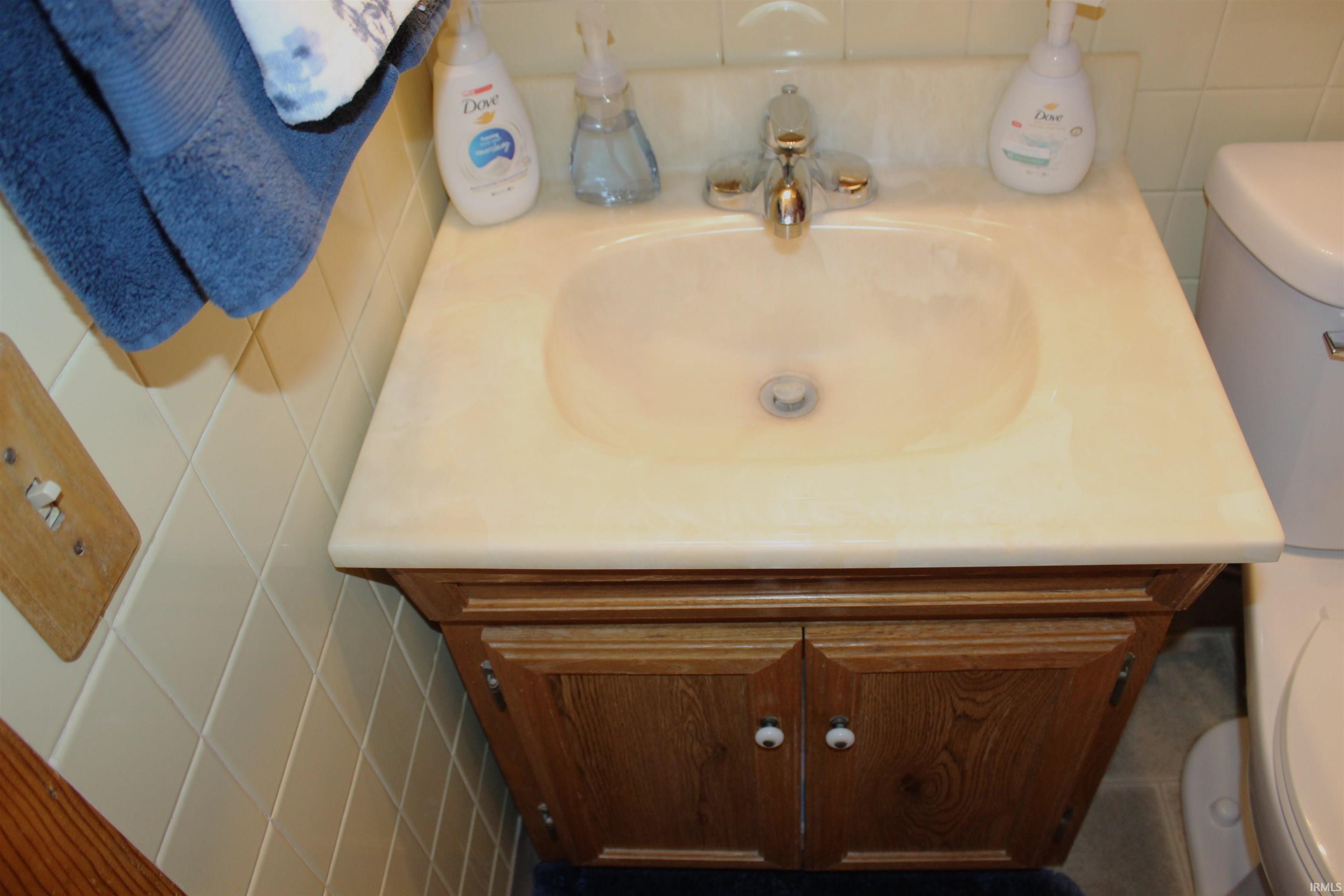 Bathroom vanity featuring a built-in sink, chrome-finish faucet, and wood-finish cabinetry