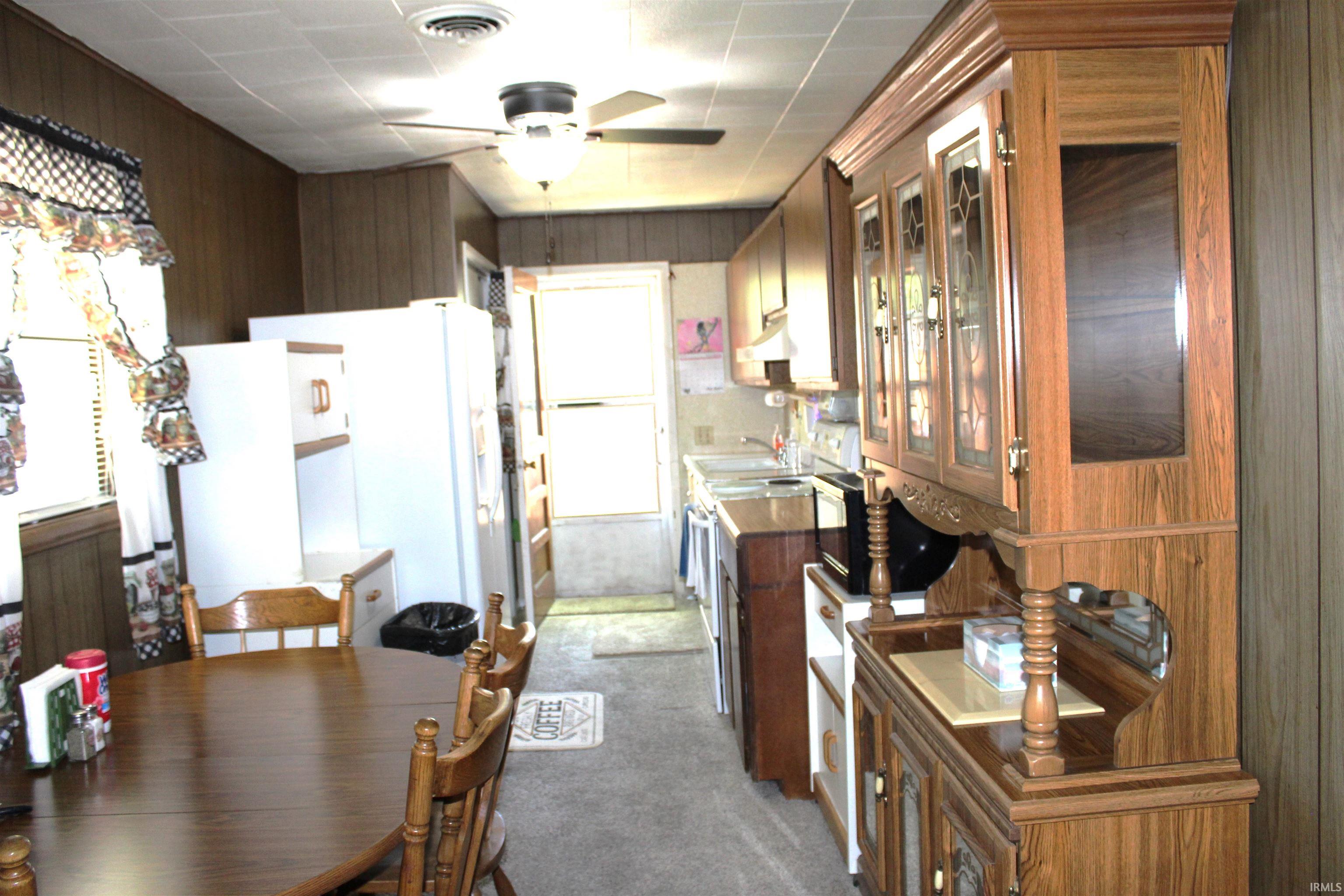 Kitchen and dining area featuring wood-paneled walls and a drop ceiling