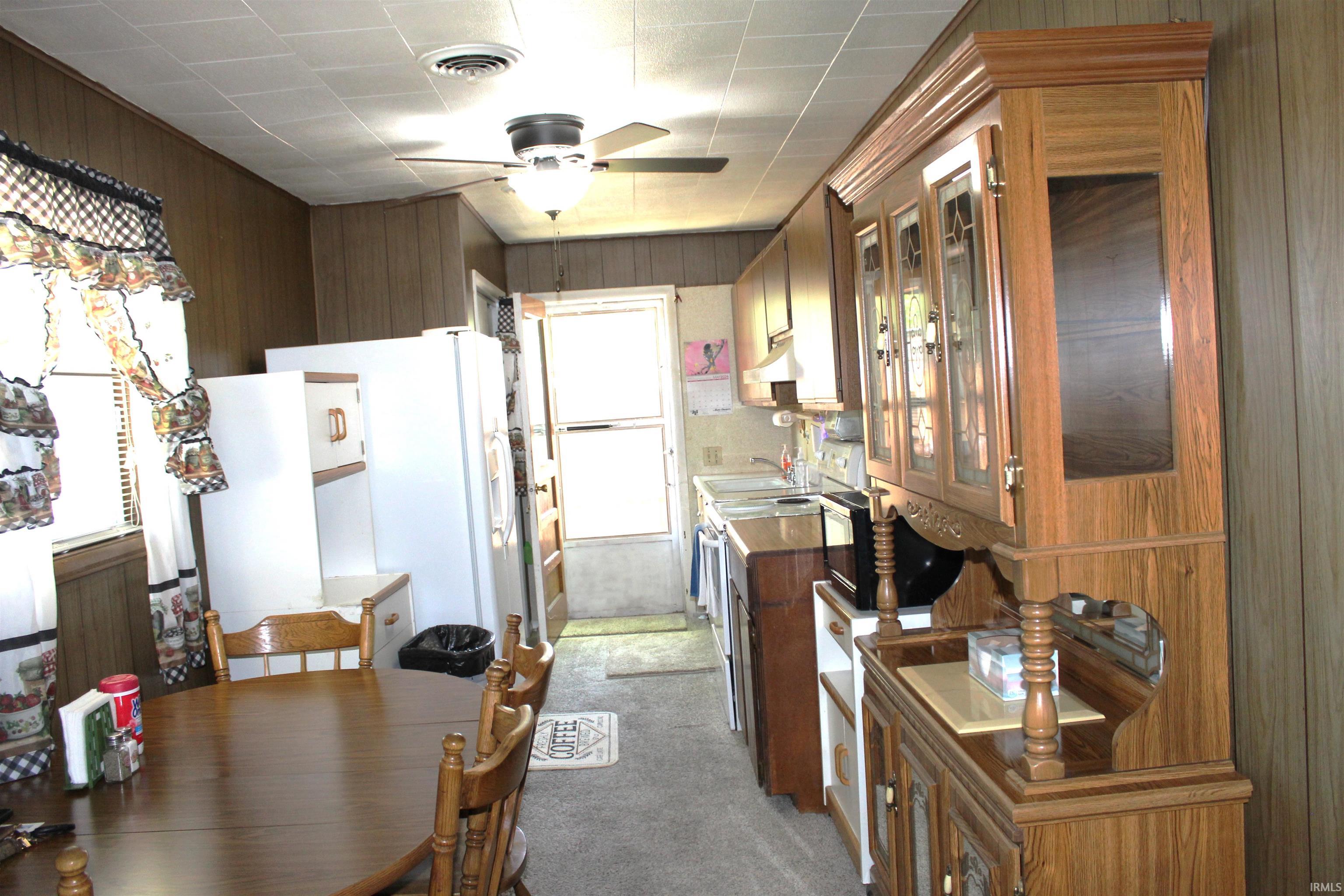 Open-concept kitchen and dining area featuring wood-paneled walls and a paneled ceiling