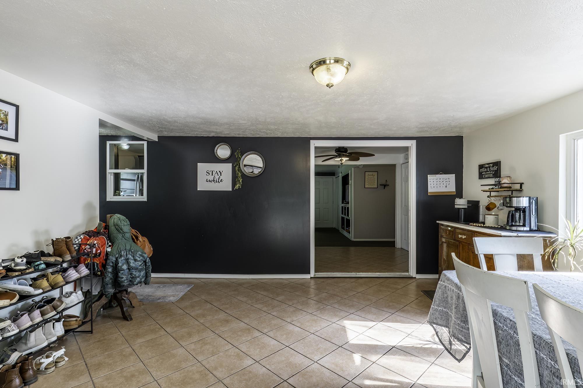 Neutral tile flooring extends through this interior space, featuring a contrasting dark accent wall