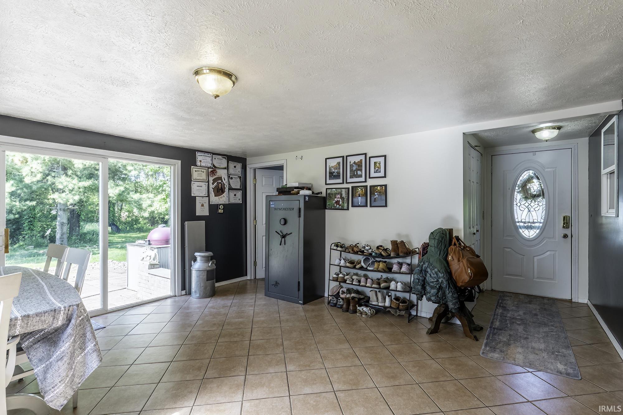 Spacious interior with tile flooring throughout, featuring a white front entry door with decorative glass