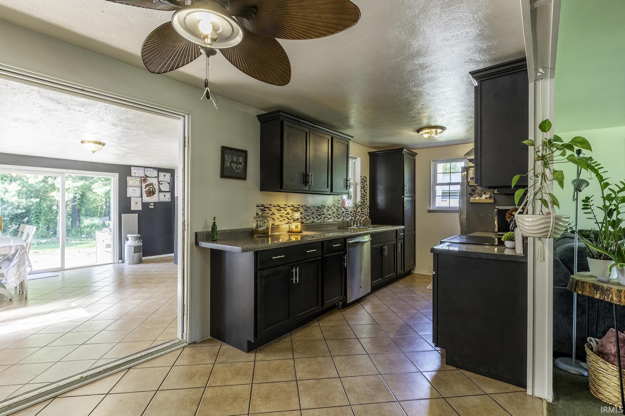Kitchen featuring dark cabinetry, stone-look countertops, and a decorative tile backsplash