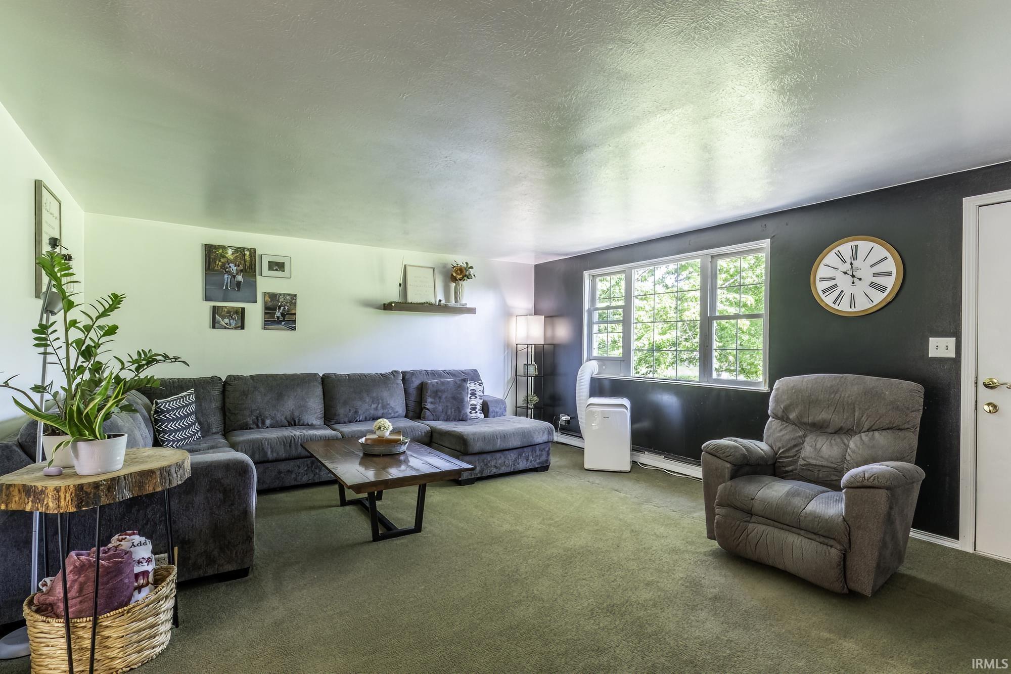 Spacious living area featuring carpet flooring, crisp white walls, and a prominent window offering abundant natural light