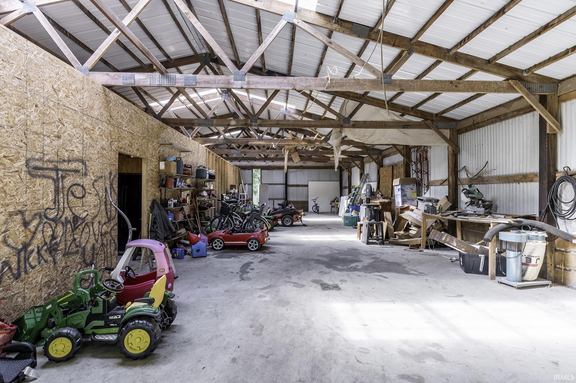 Spacious outbuilding featuring exposed wood framing, a metal roof, and a concrete floor