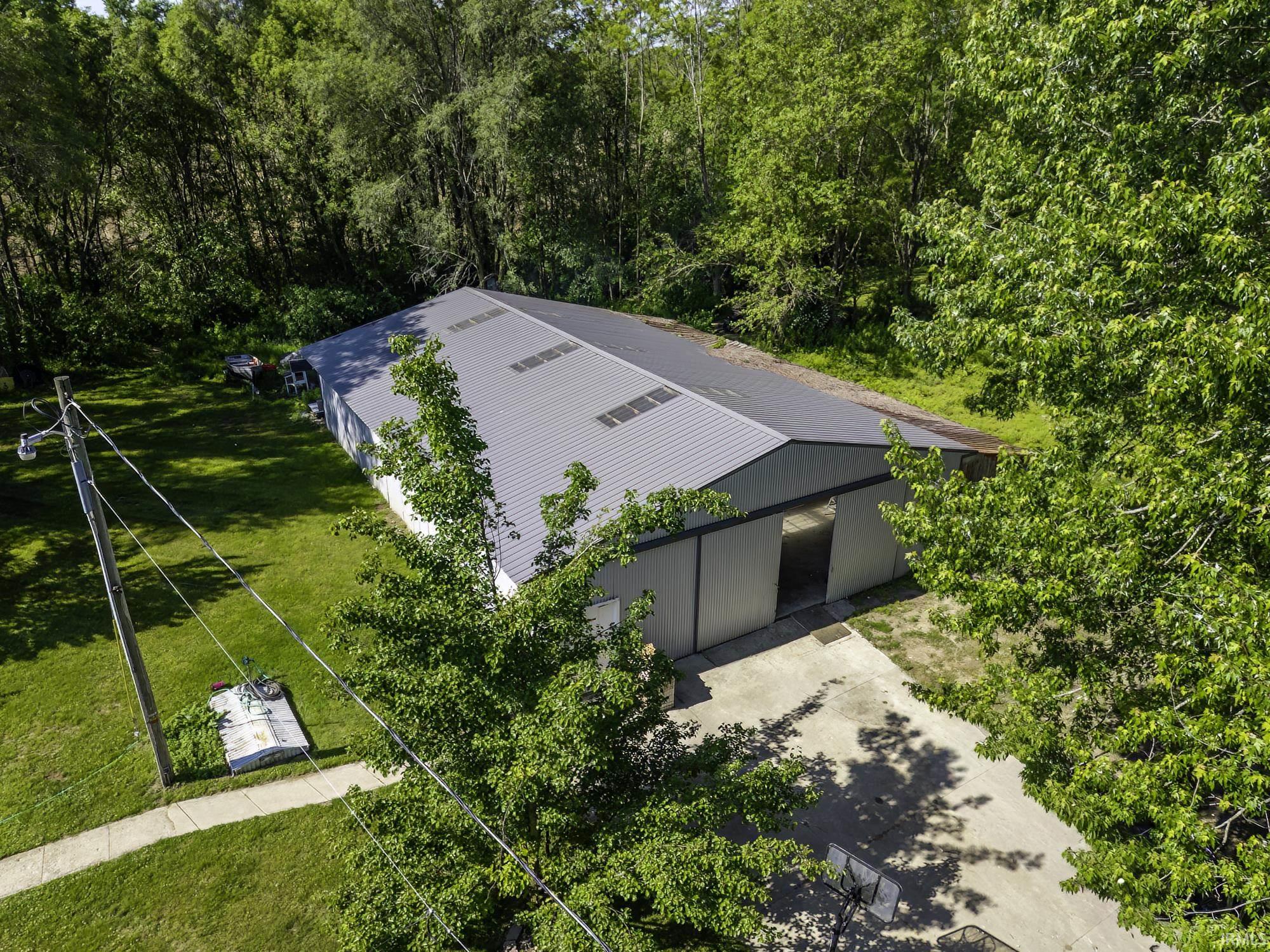 Spacious metal-sided building featuring a grey metal roof with skylights, multiple large bays with open entrances, and a concrete approach