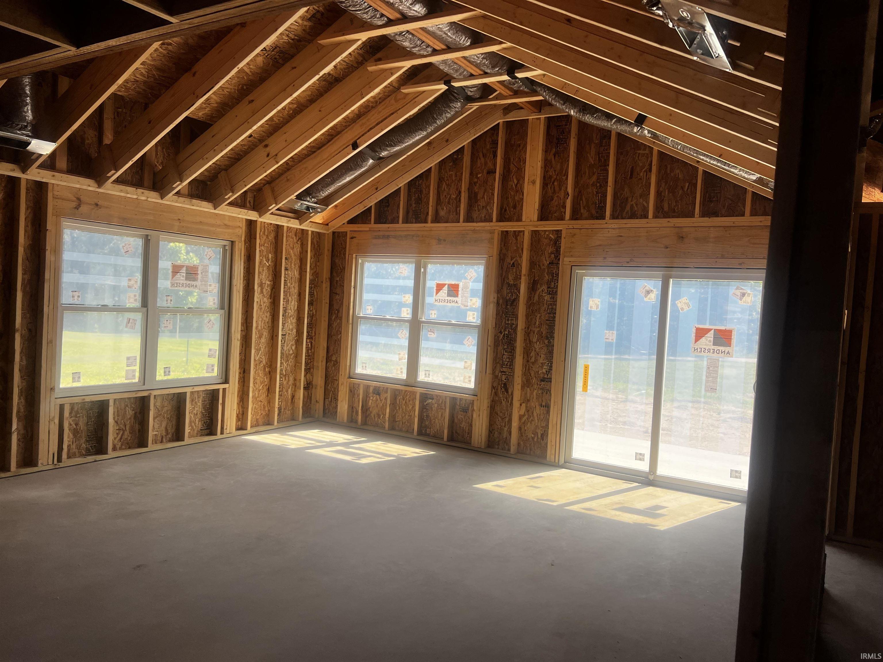 Spacious room under construction featuring exposed wood framing and vaulted ceilings