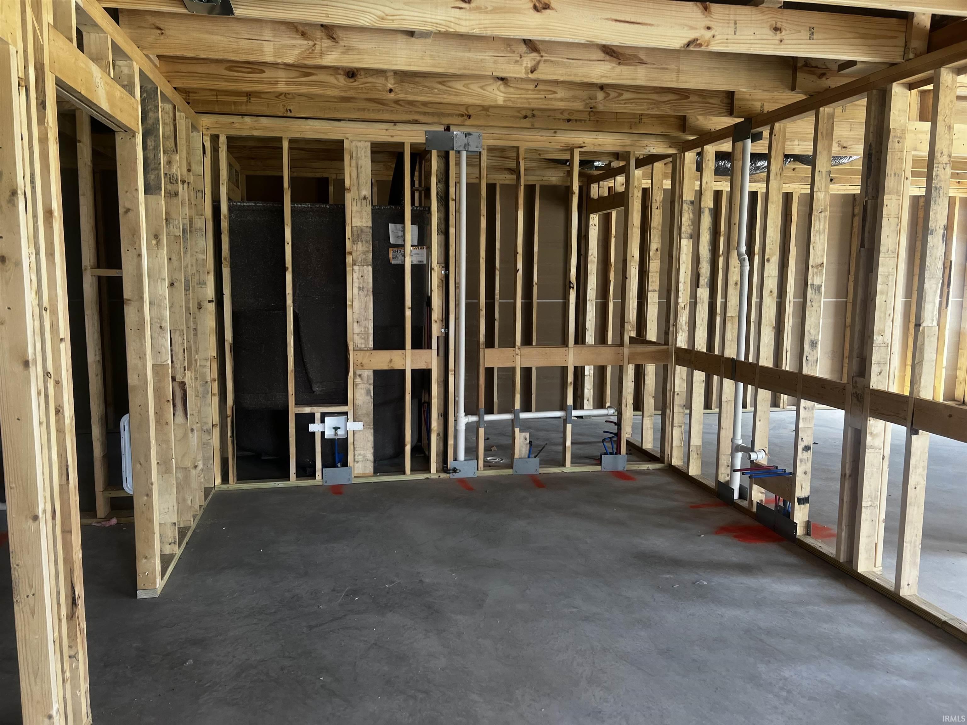 Interior space showcasing wood framing and concrete subflooring