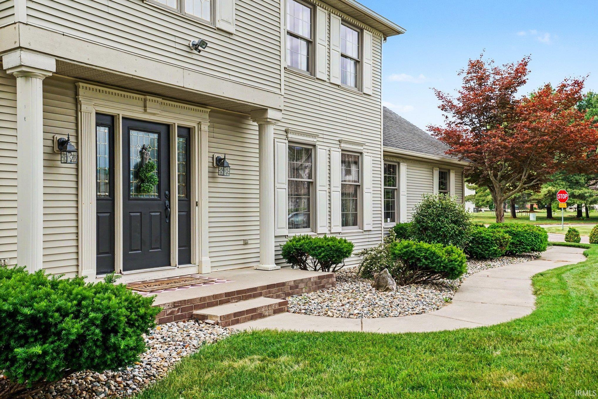 Inviting entry featuring a paneled front door with sidelights, two exterior lanterns, and a brick-step stoop