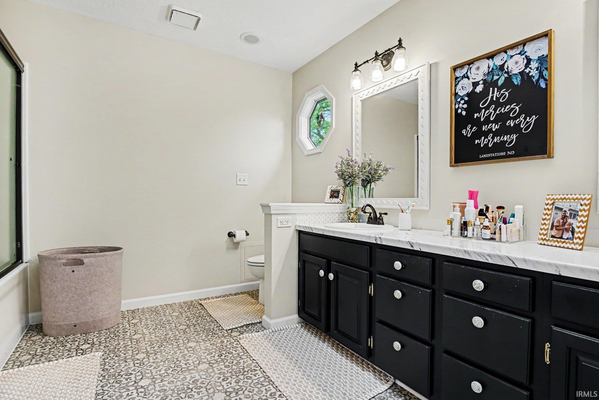 Double vanity with black cabinetry, white countertops, and a single basin sink