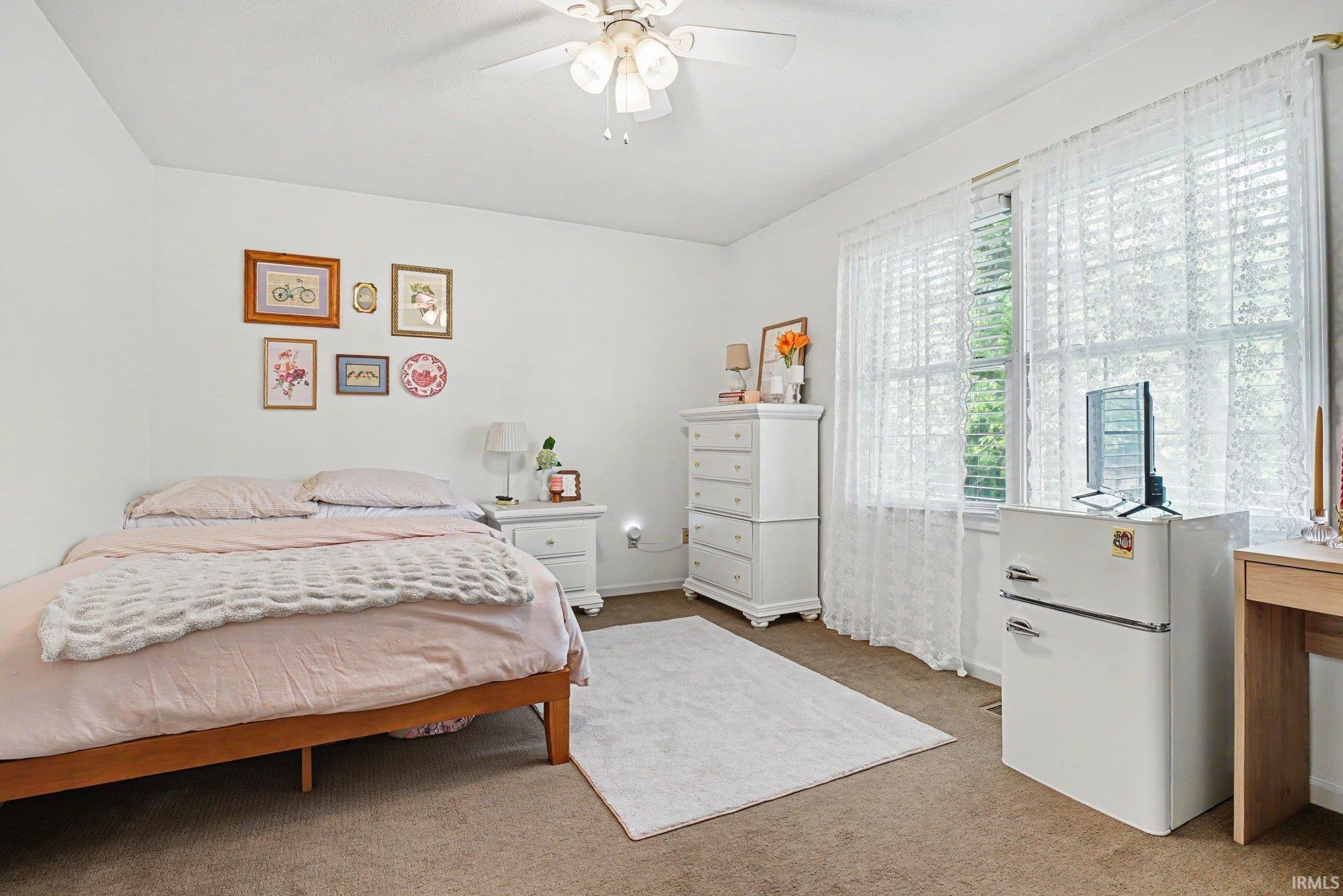 Carpeted room featuring white walls and a white ceiling fan with integrated lighting