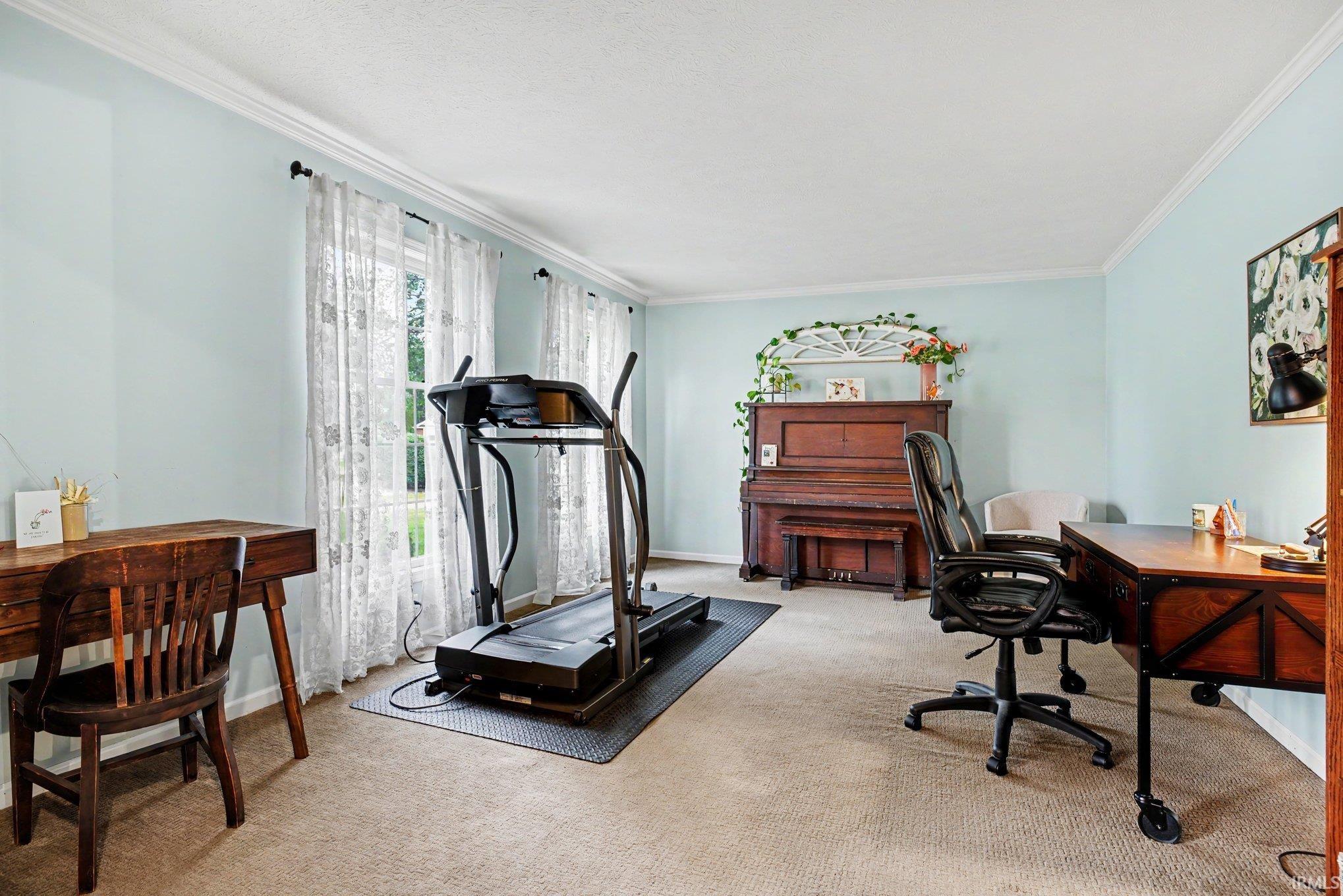 Spacious room featuring light blue walls, two large windows with white trim, and crown molding