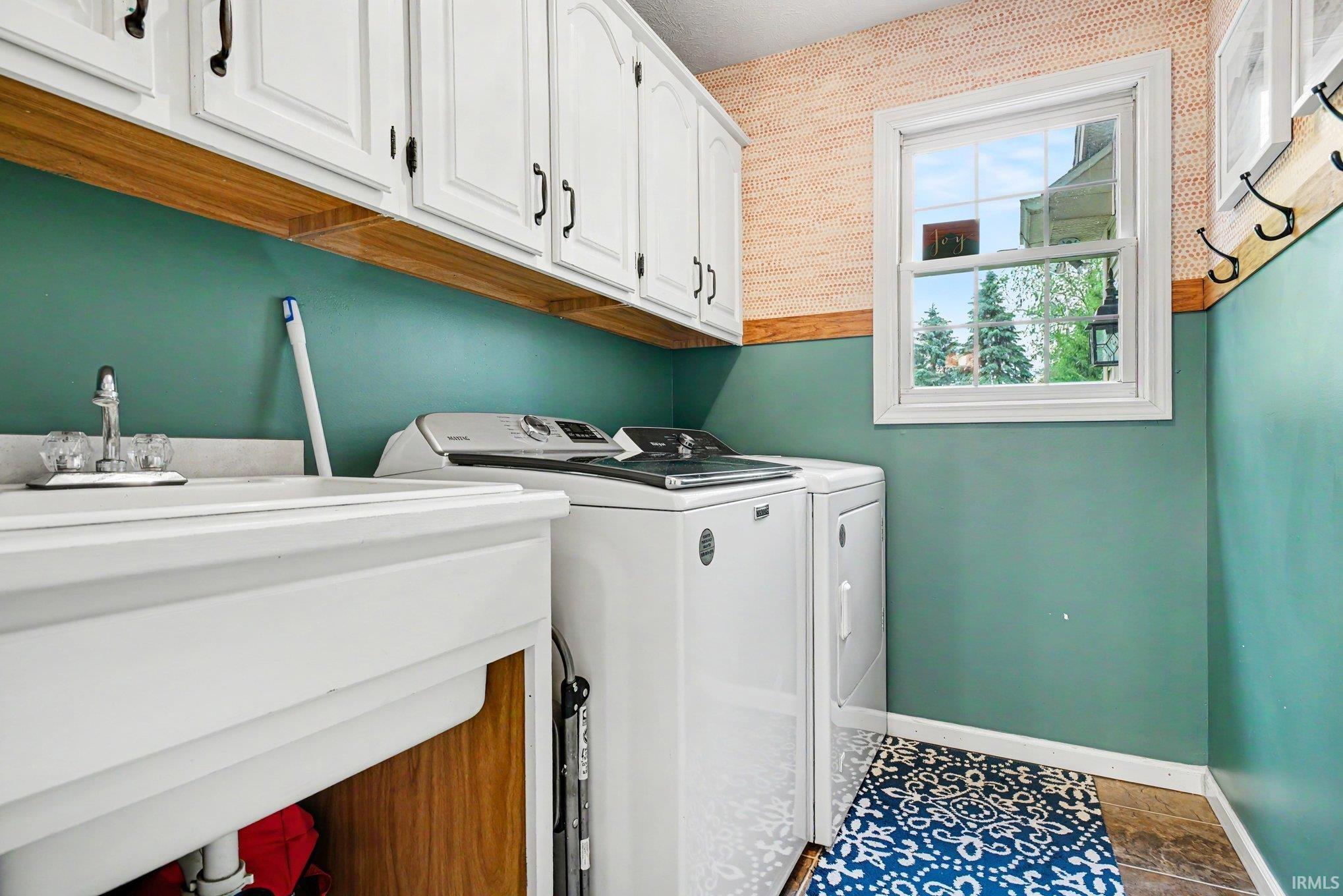Laundry area featuring white cabinetry, a utility sink, and a window with exterior visibility
