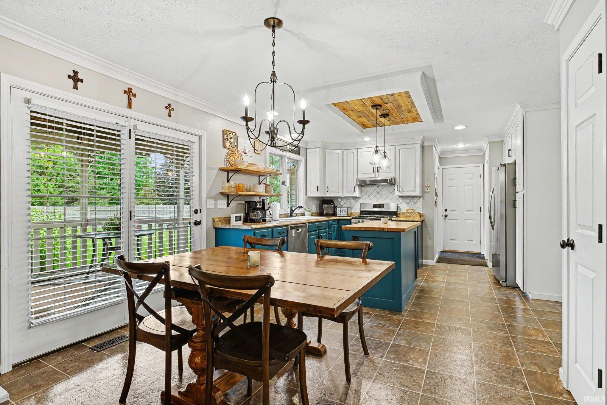 Spacious kitchen and dining area with tile flooring, double glass panel doors, and a wood-paneled ceiling feature