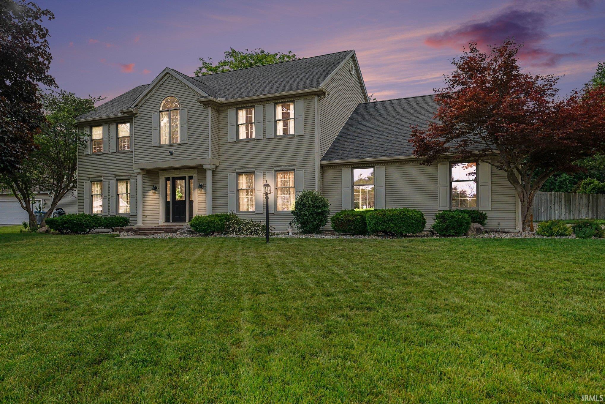 Traditional two-story residence featuring light-colored siding, a dark roof, and a prominent front entry with columns