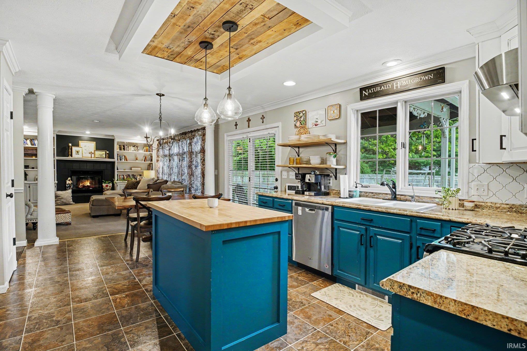 Open-concept kitchen featuring a wood-finish island countertop, teal cabinetry, and granite countertops