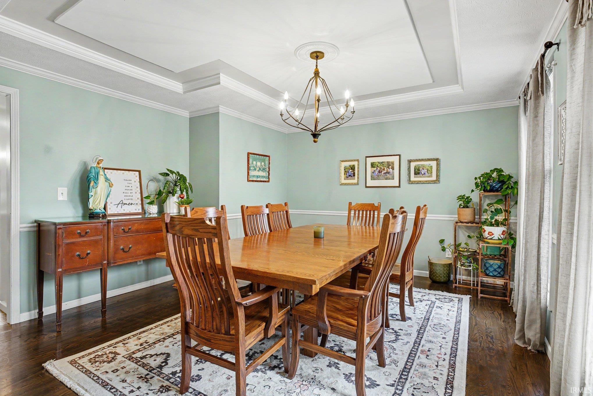 Dining room featuring a tray ceiling, crown molding, and wainscoting