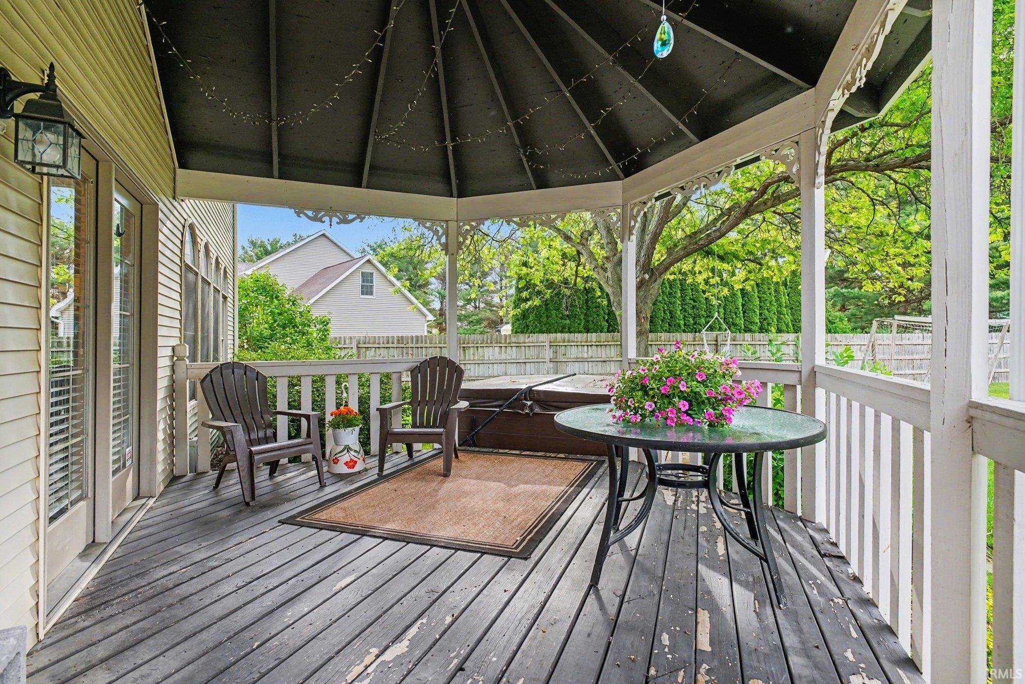 Covered outdoor deck with white baluster railing and a dark wood-finish floor