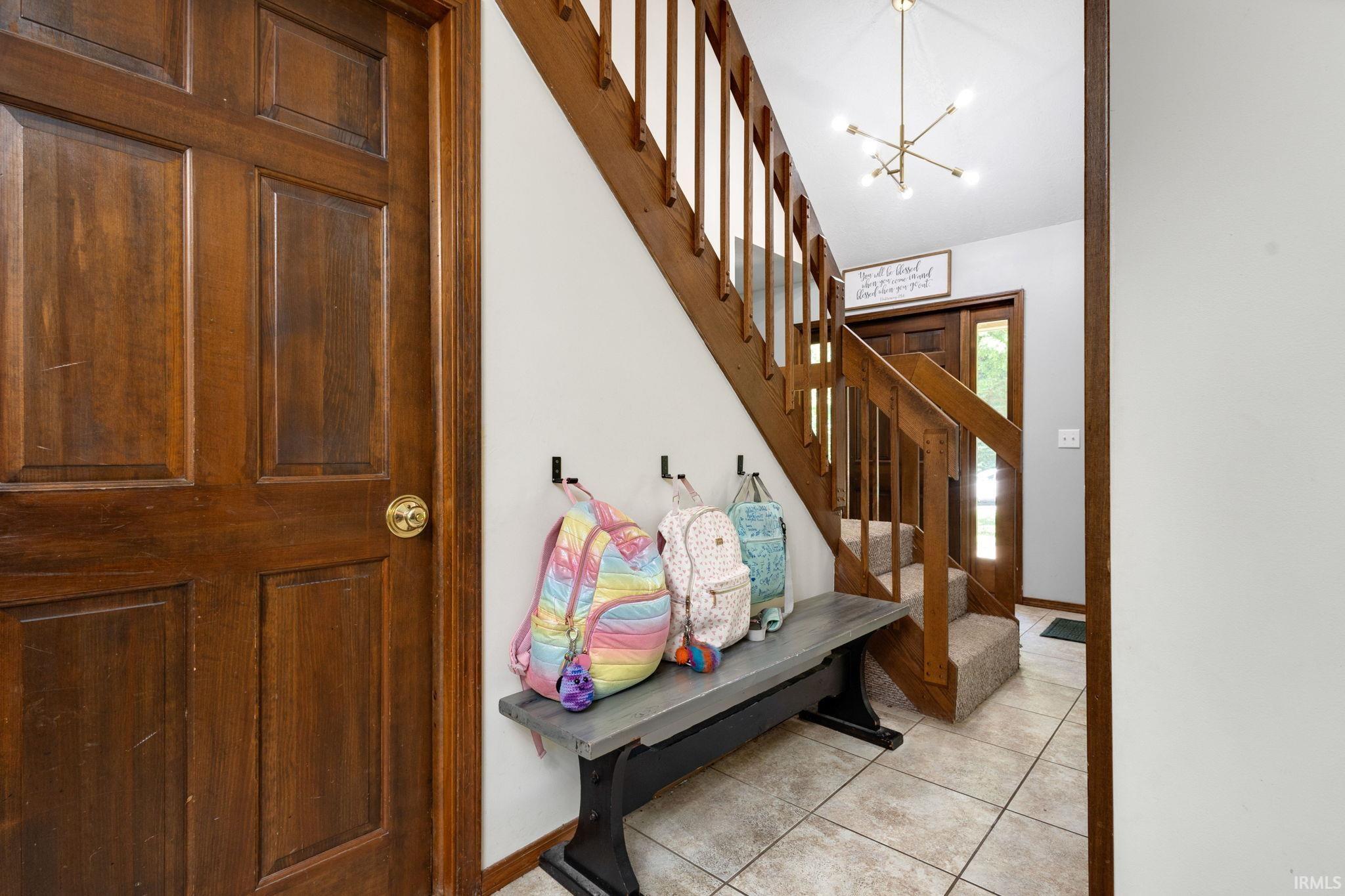 Foyer featuring a wood-panel door, wood staircase with carpeted treads, and tiled flooring