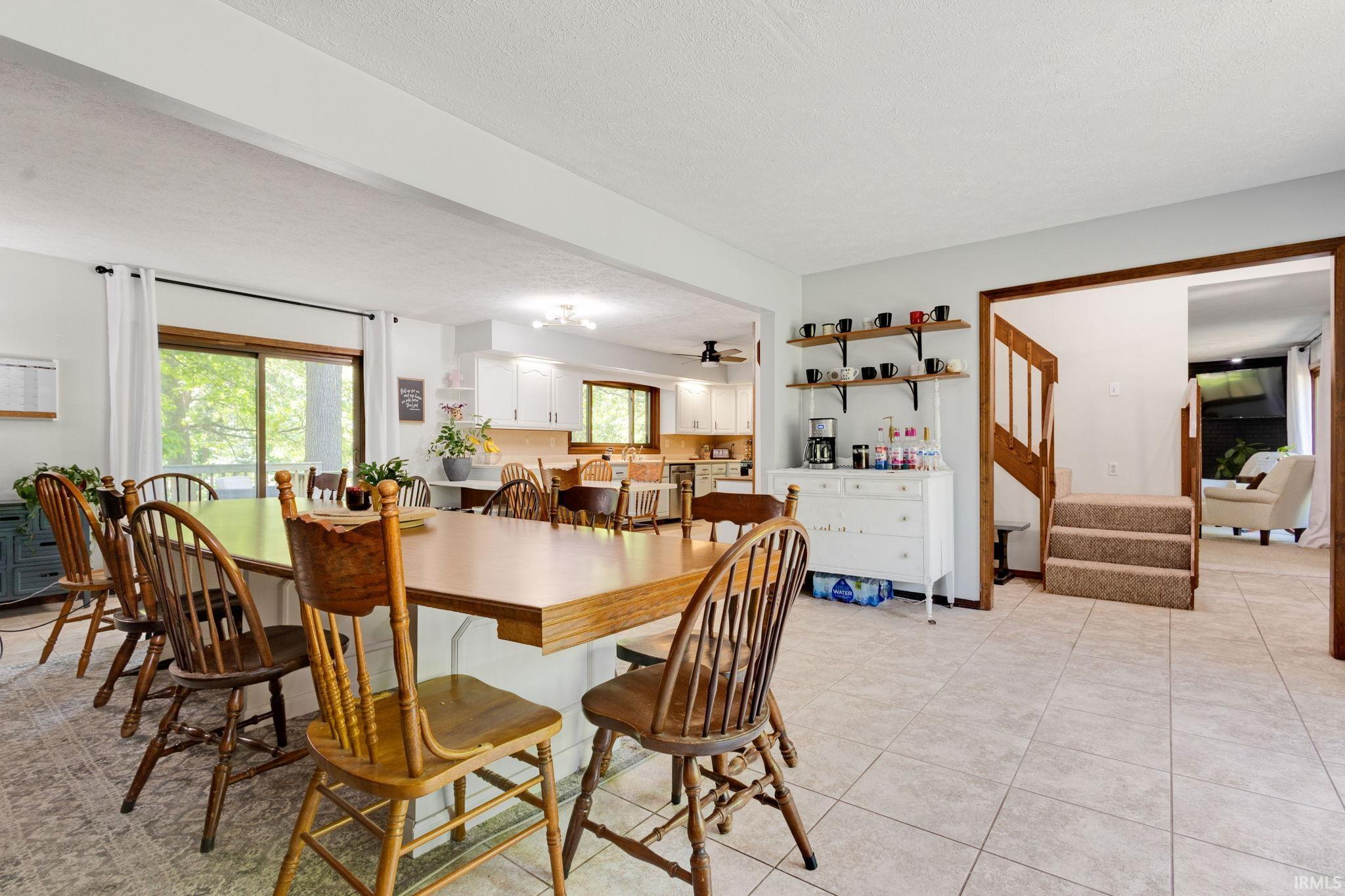 Spacious open-concept area featuring tile flooring, a large island with wood-finish countertop, and sliding glass doors