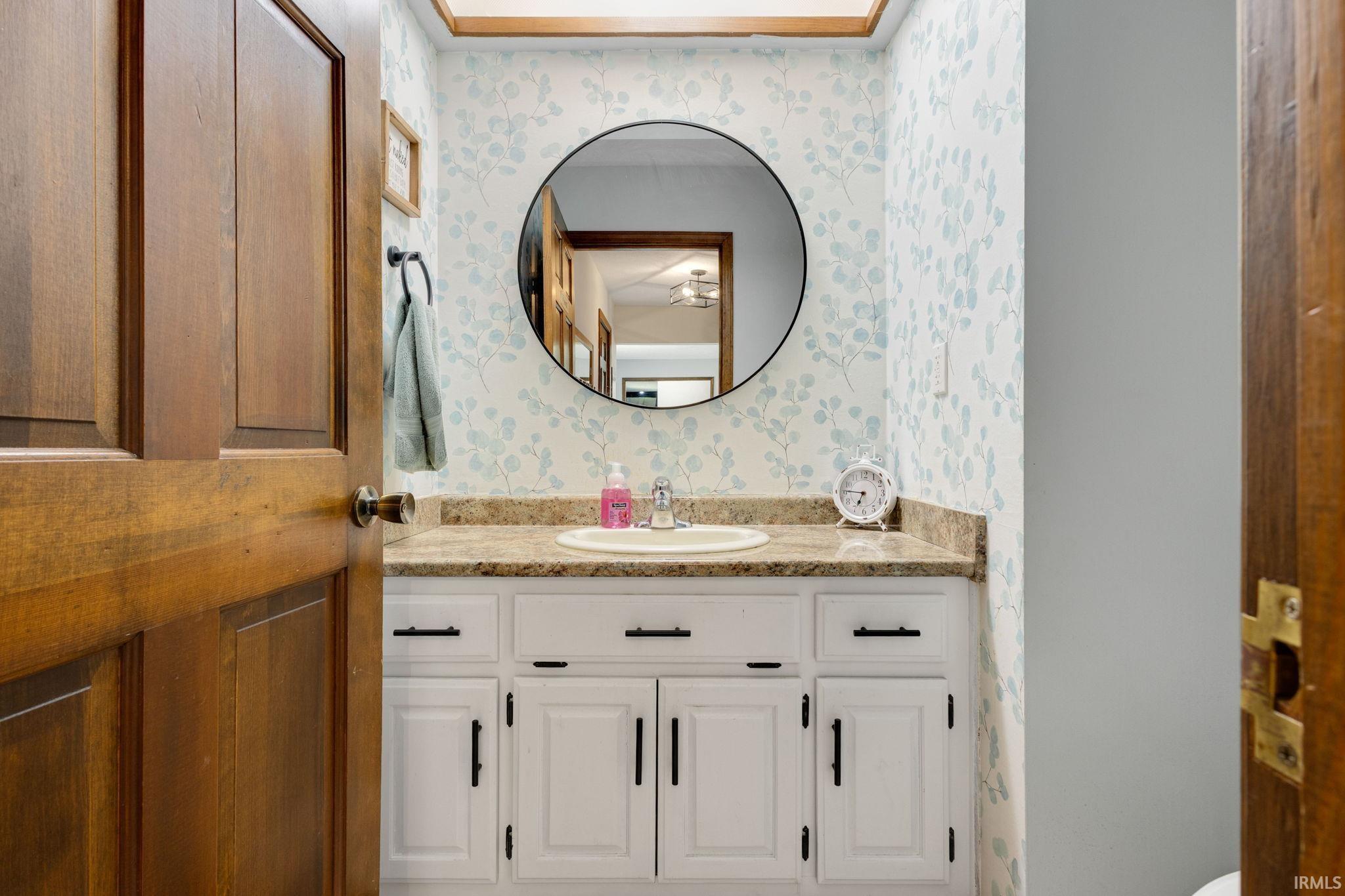 Vanity with white cabinetry, matte black hardware, and a stone-finish countertop