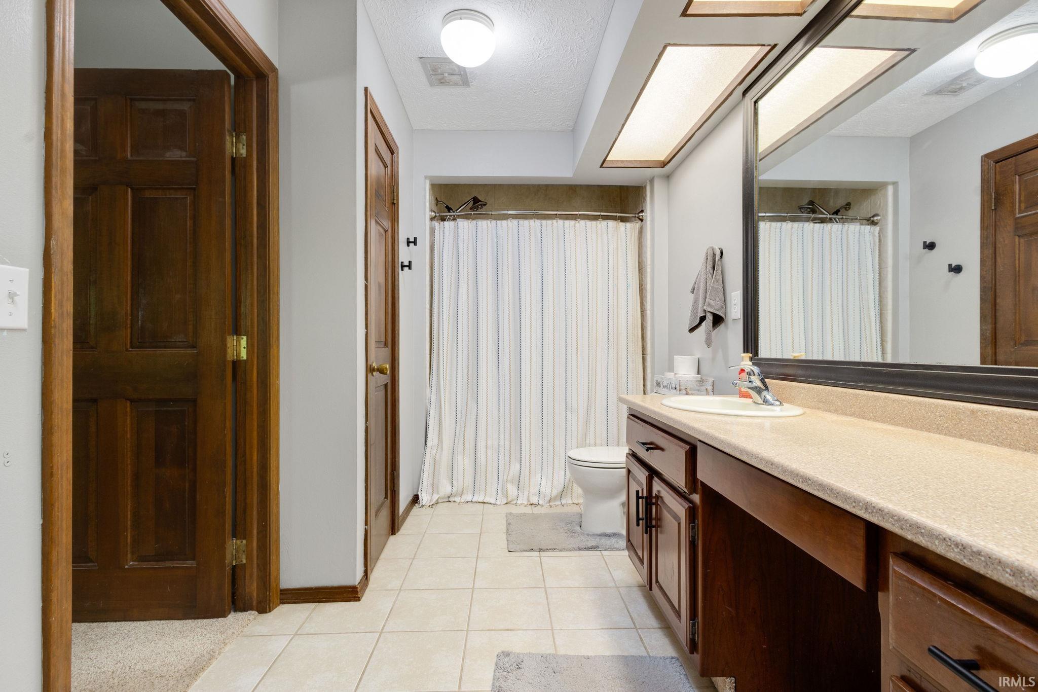Bathroom featuring a single vanity with an integrated sink, rich wood-finish cabinetry, and a spacious framed mirror