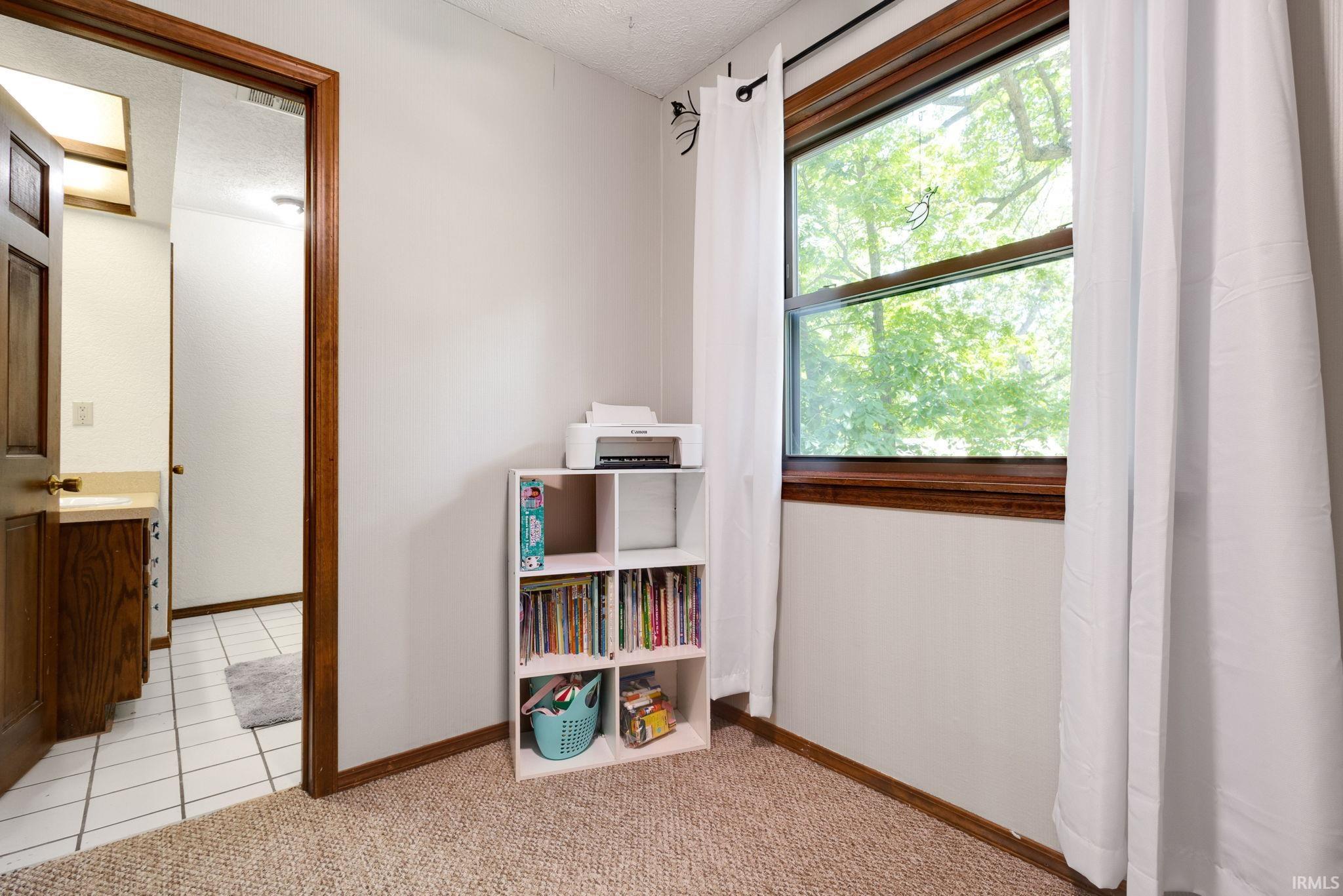 Carpeted room with a wooden window frame and white curtains