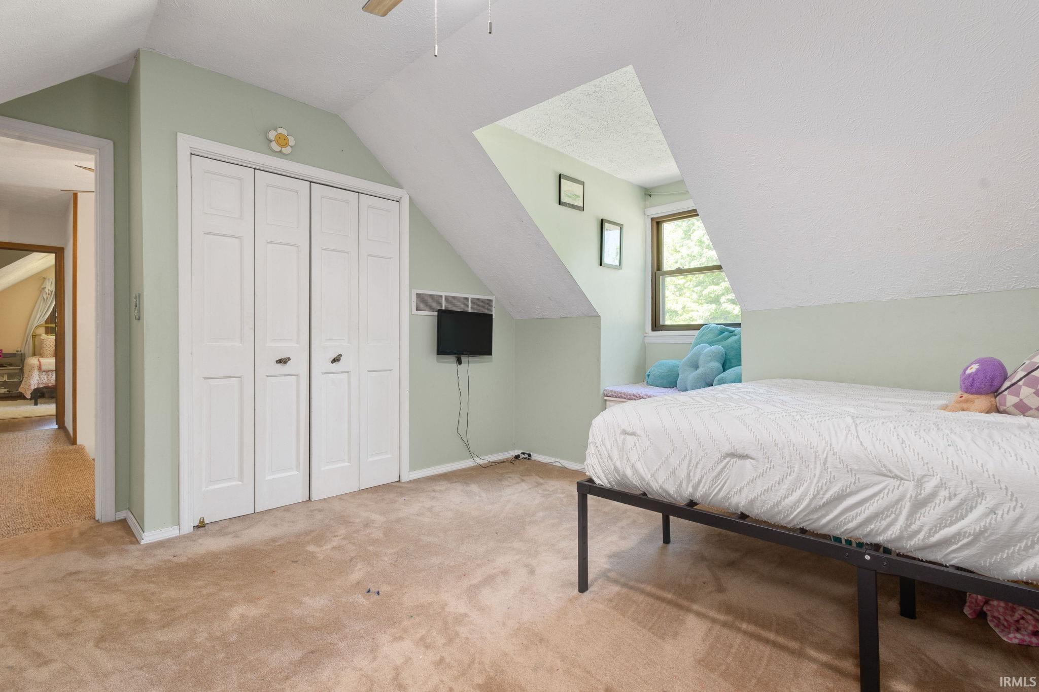 Bedroom featuring sloped ceilings, a window nook, and neutral carpeting