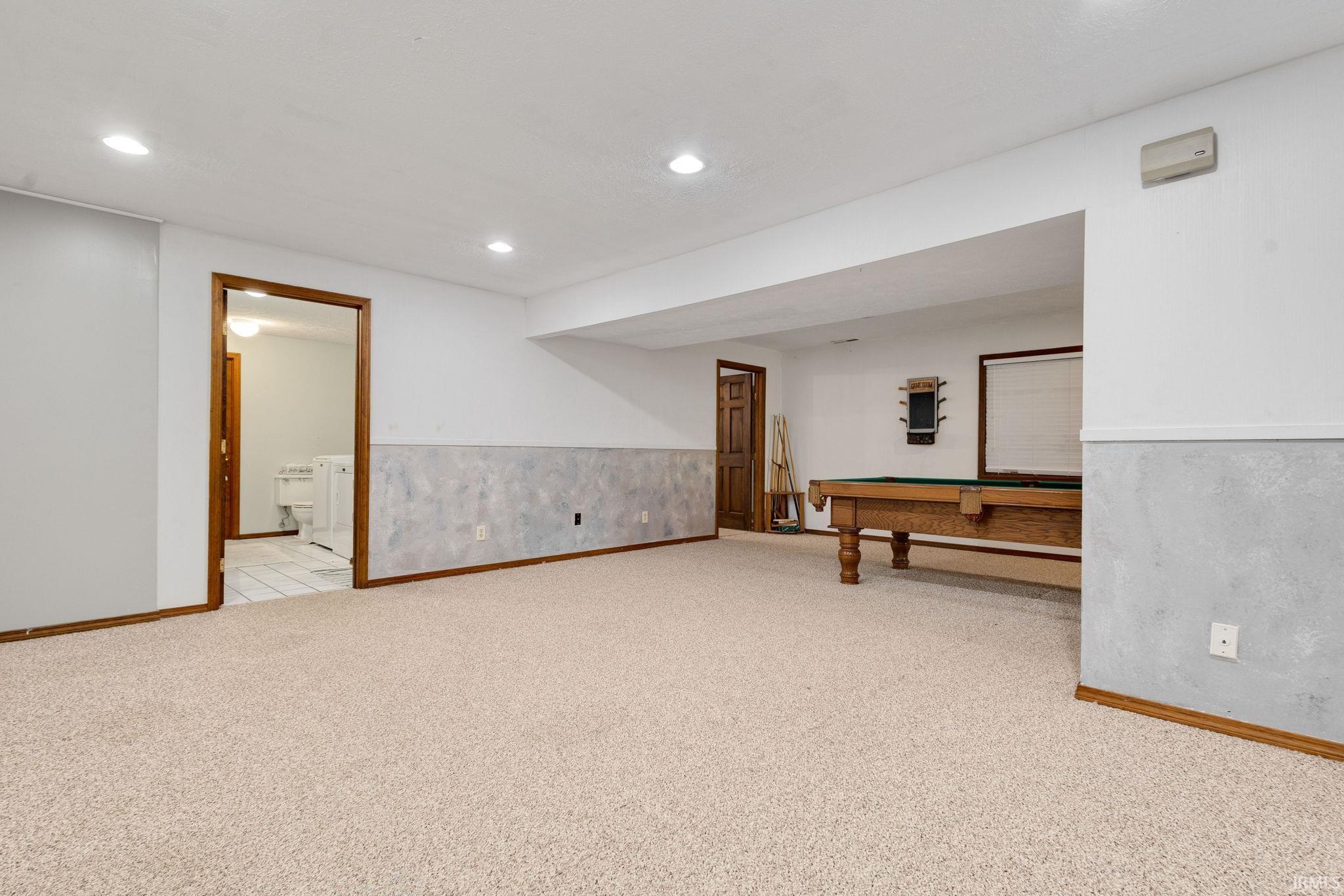 Expansive carpeted room featuring recessed lighting, a built-in pool table, and wood trim