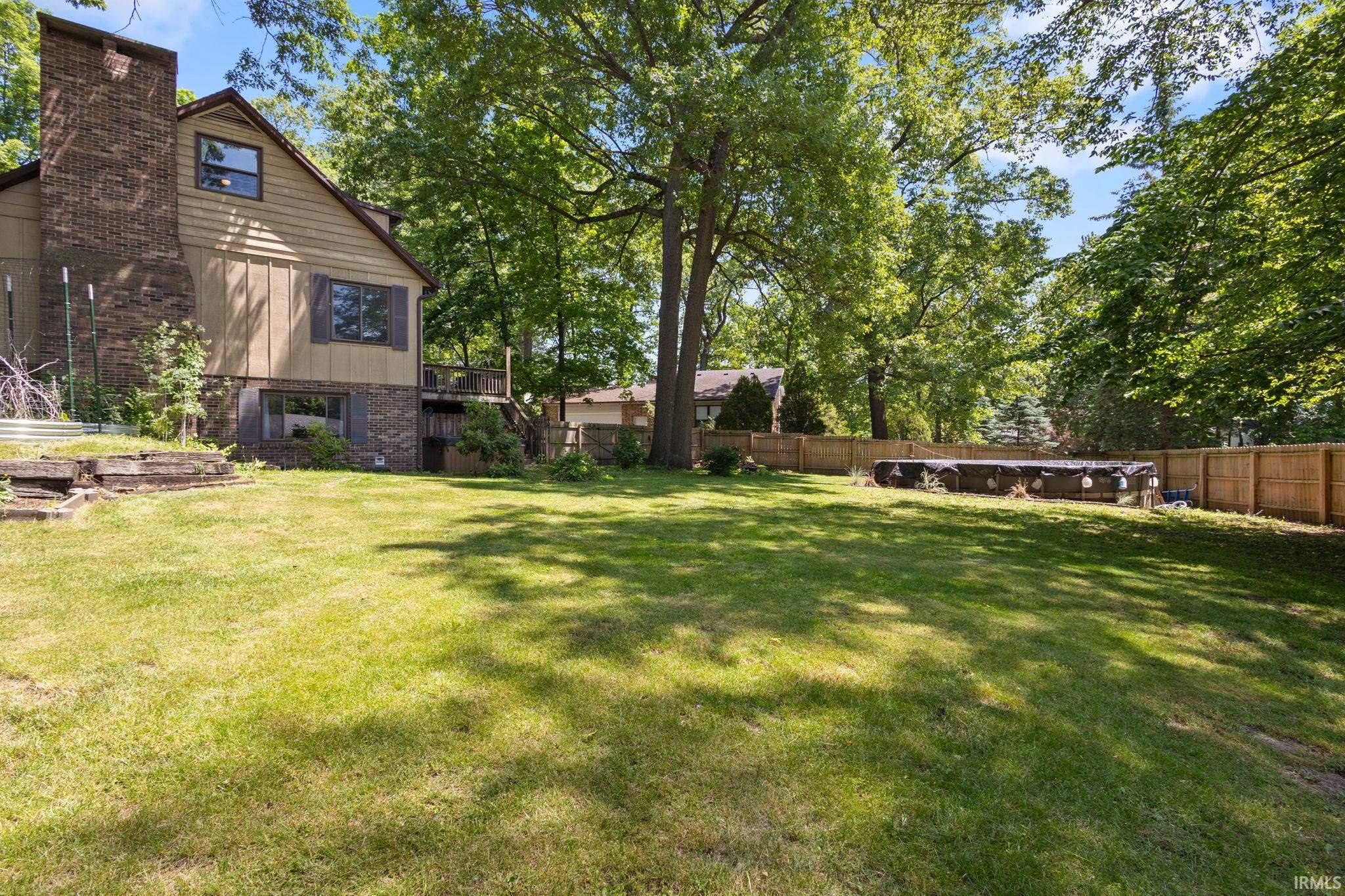 Expansive rear yard featuring a manicured lawn, established perimeter fencing, and mature trees