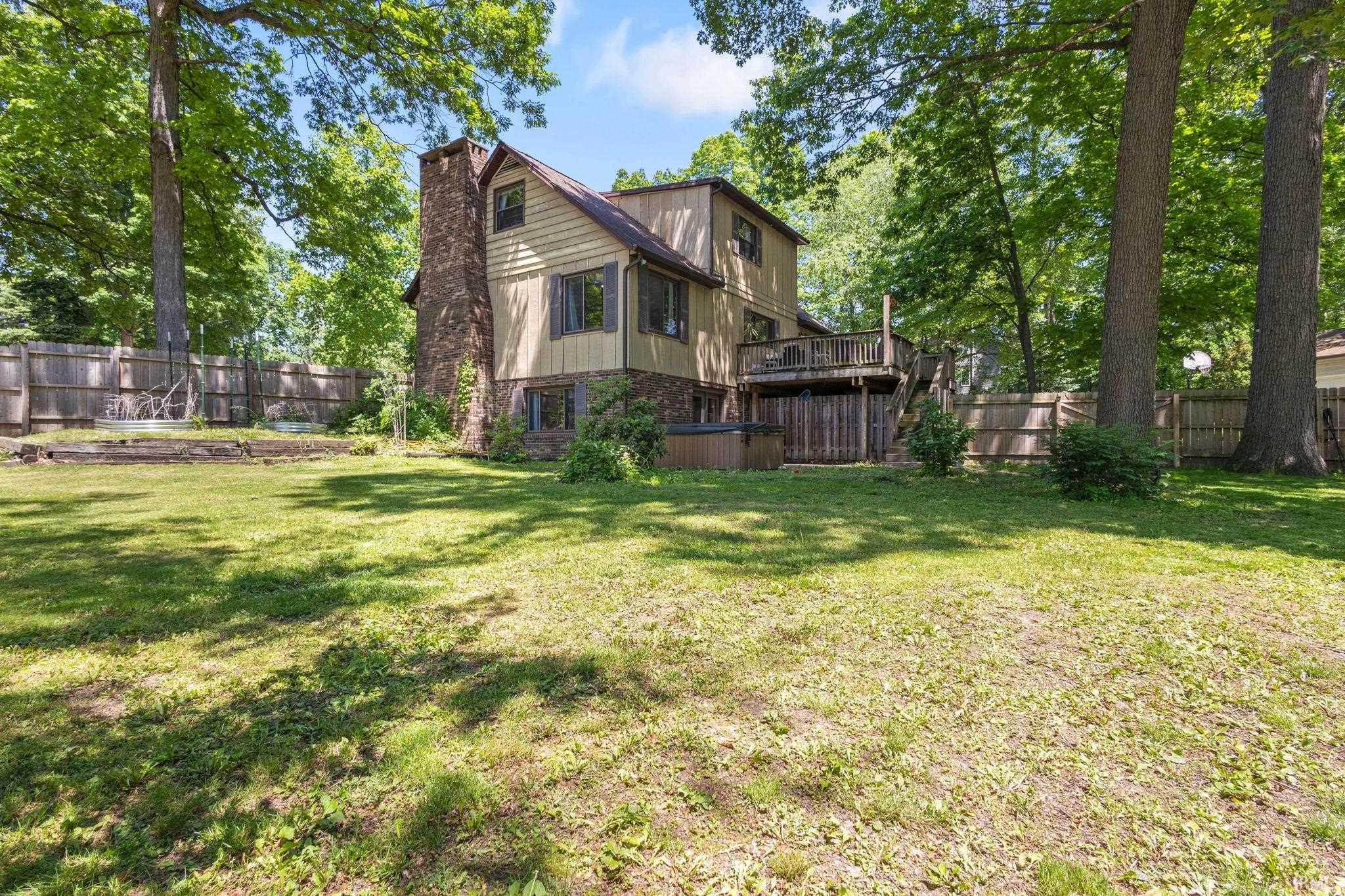 Rear exterior featuring a multi-level wood deck, a stone and siding facade, and a prominent stone chimney