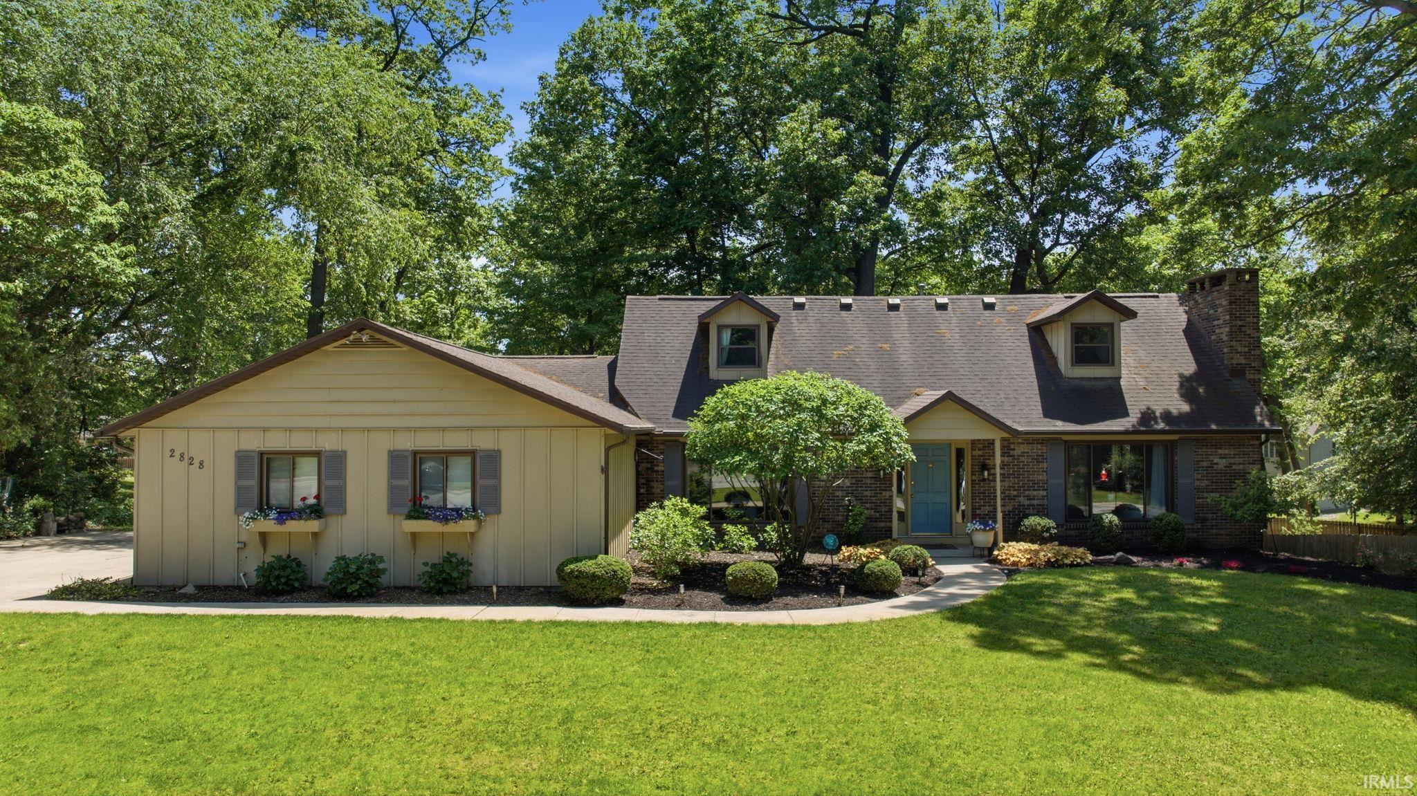 Traditional exterior with a light yellow facade and dark gray shutters, featuring a bright blue entry door