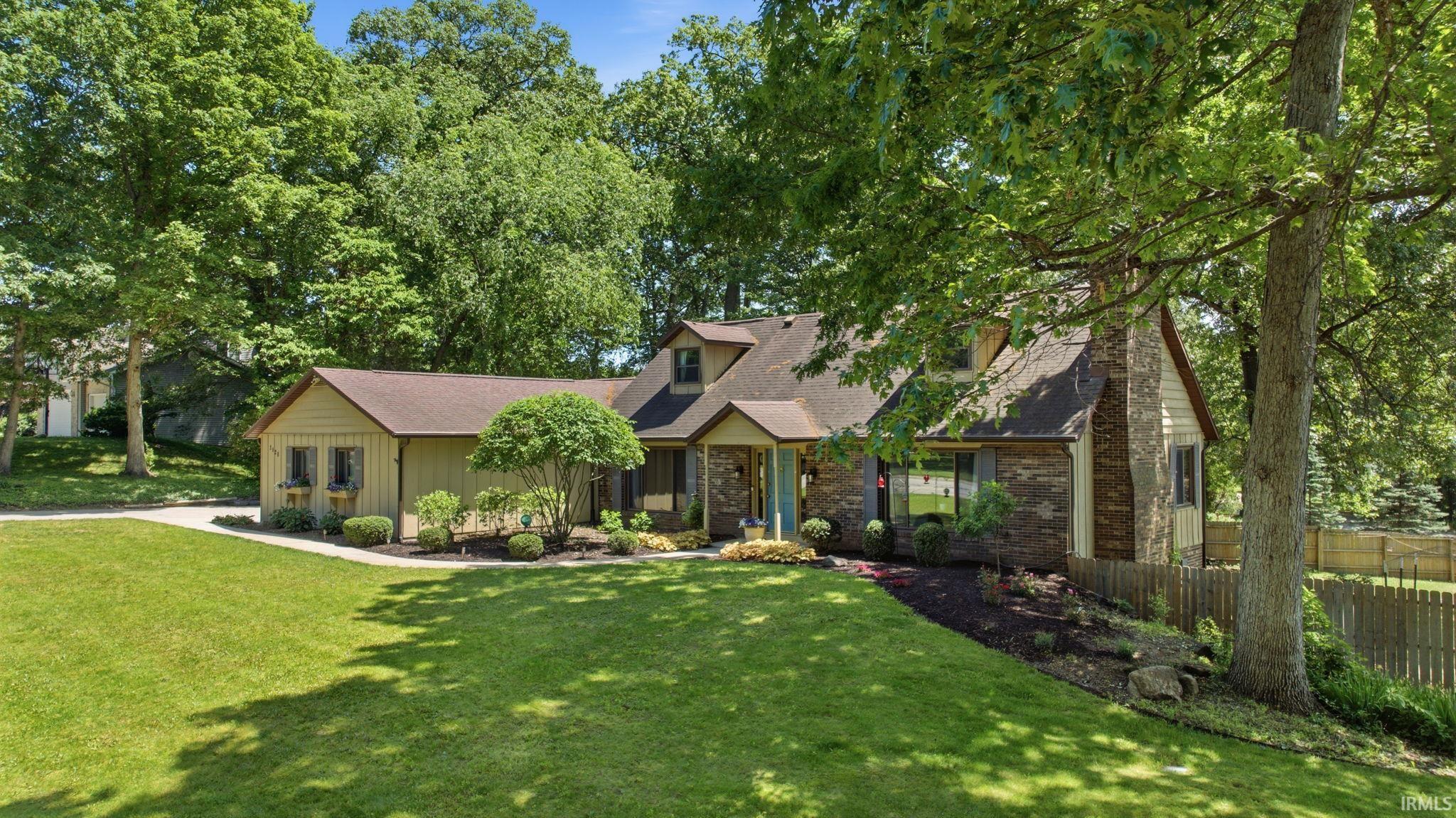 Ranch-style residence featuring a prominent front lawn, mature trees, and a concrete driveway