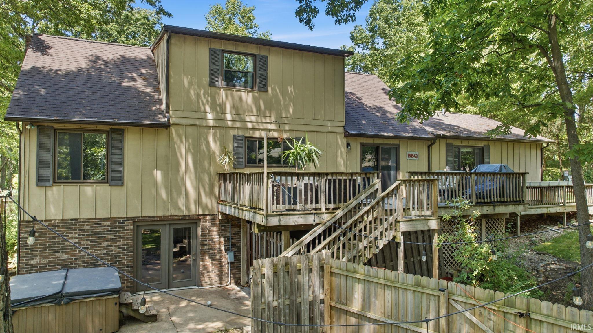 Multi-level rear exterior featuring extensive decking, a walk-out lower patio, and a private fenced area