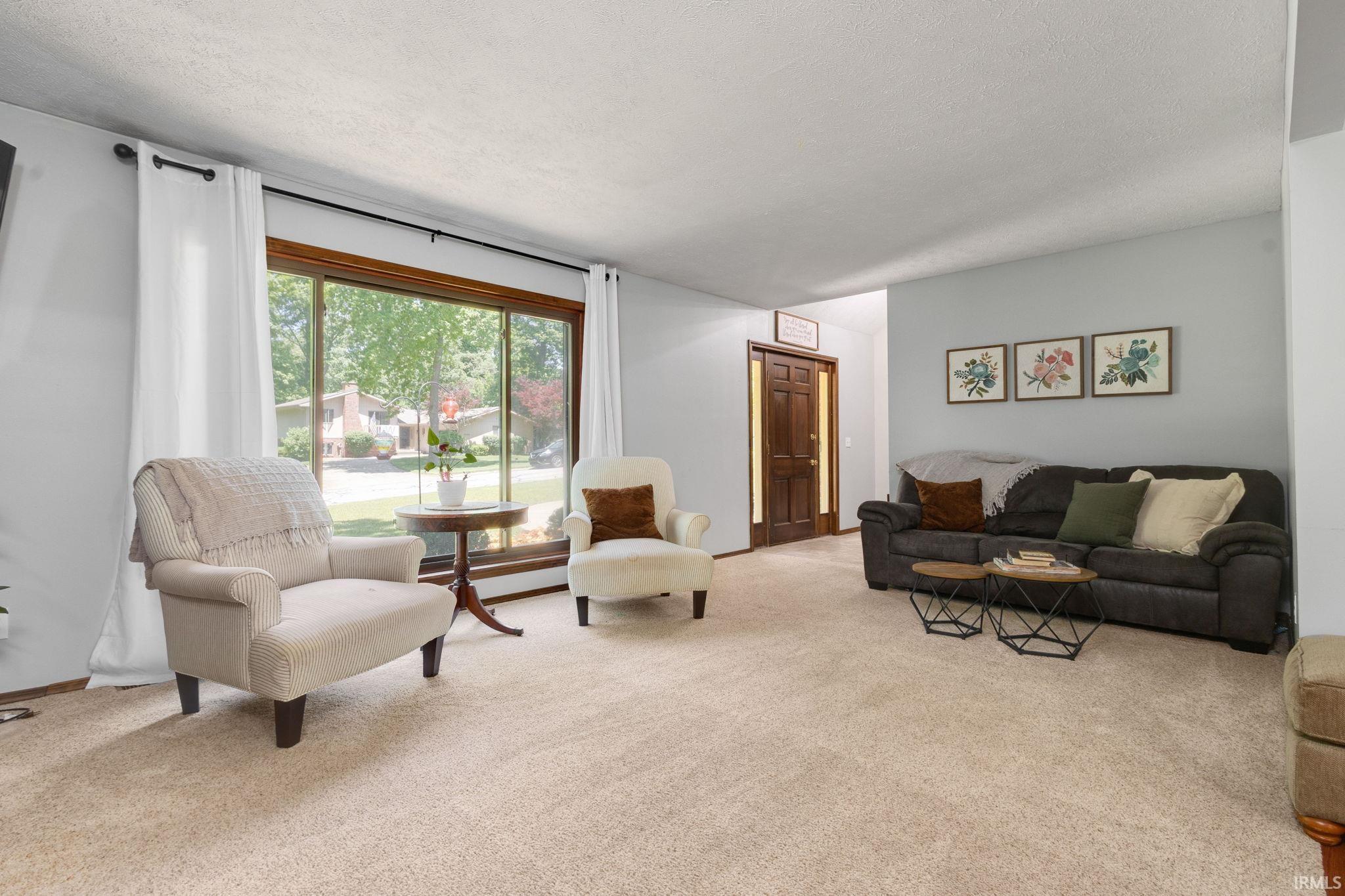 Spacious living area featuring light-toned carpeting and neutral wall colors