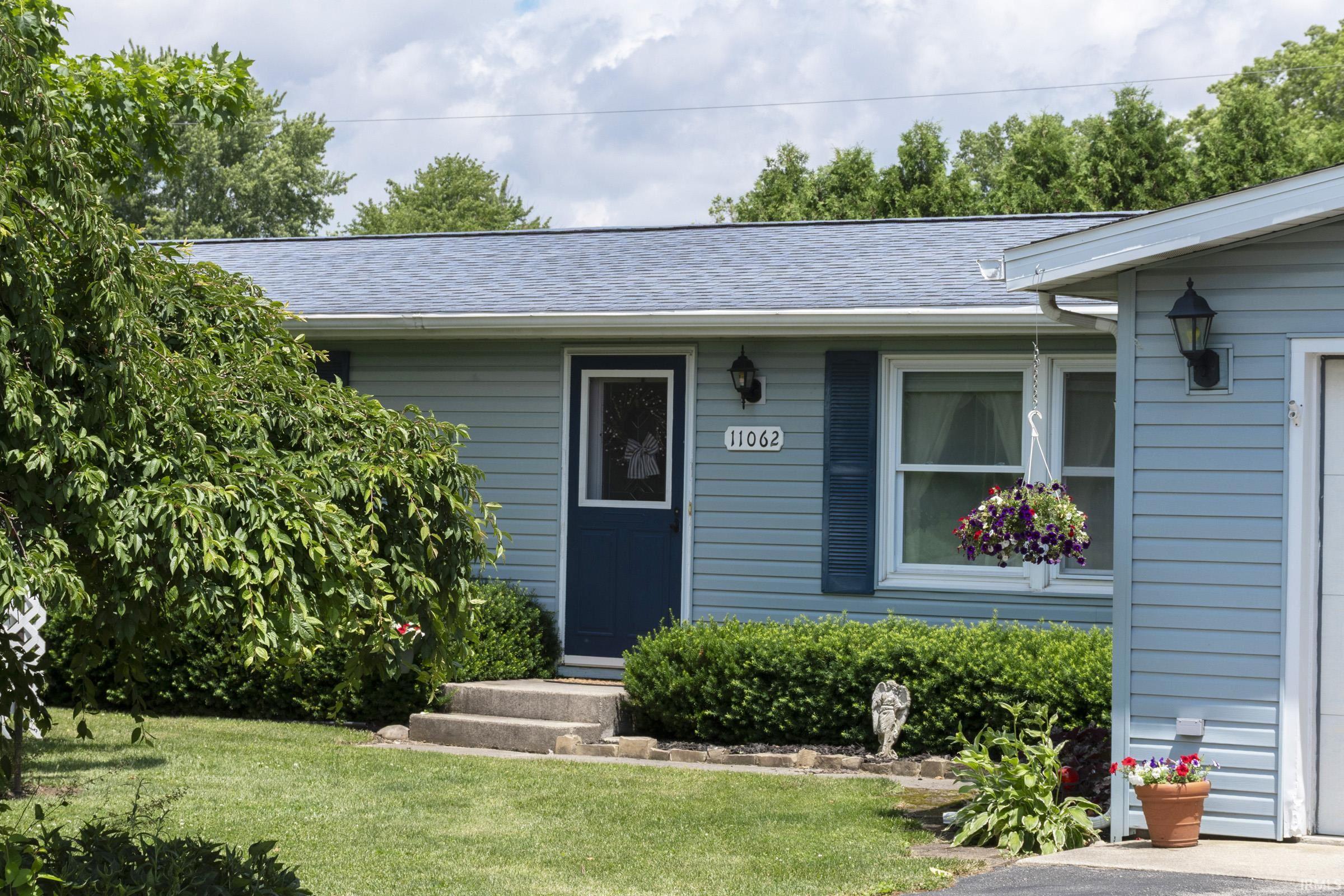 Light blue siding exterior featuring a dark blue entry door, dark blue window shutters, and a gray shingle roof