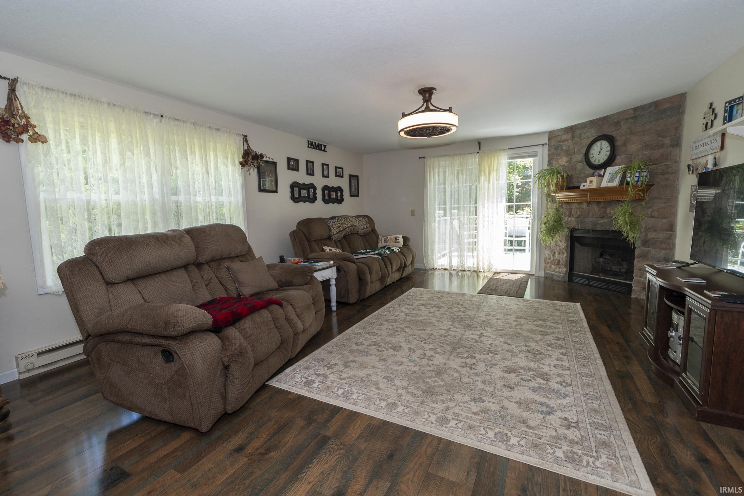 Living area featuring rich wood-finish flooring and a stone-accented fireplace with a wood mantel