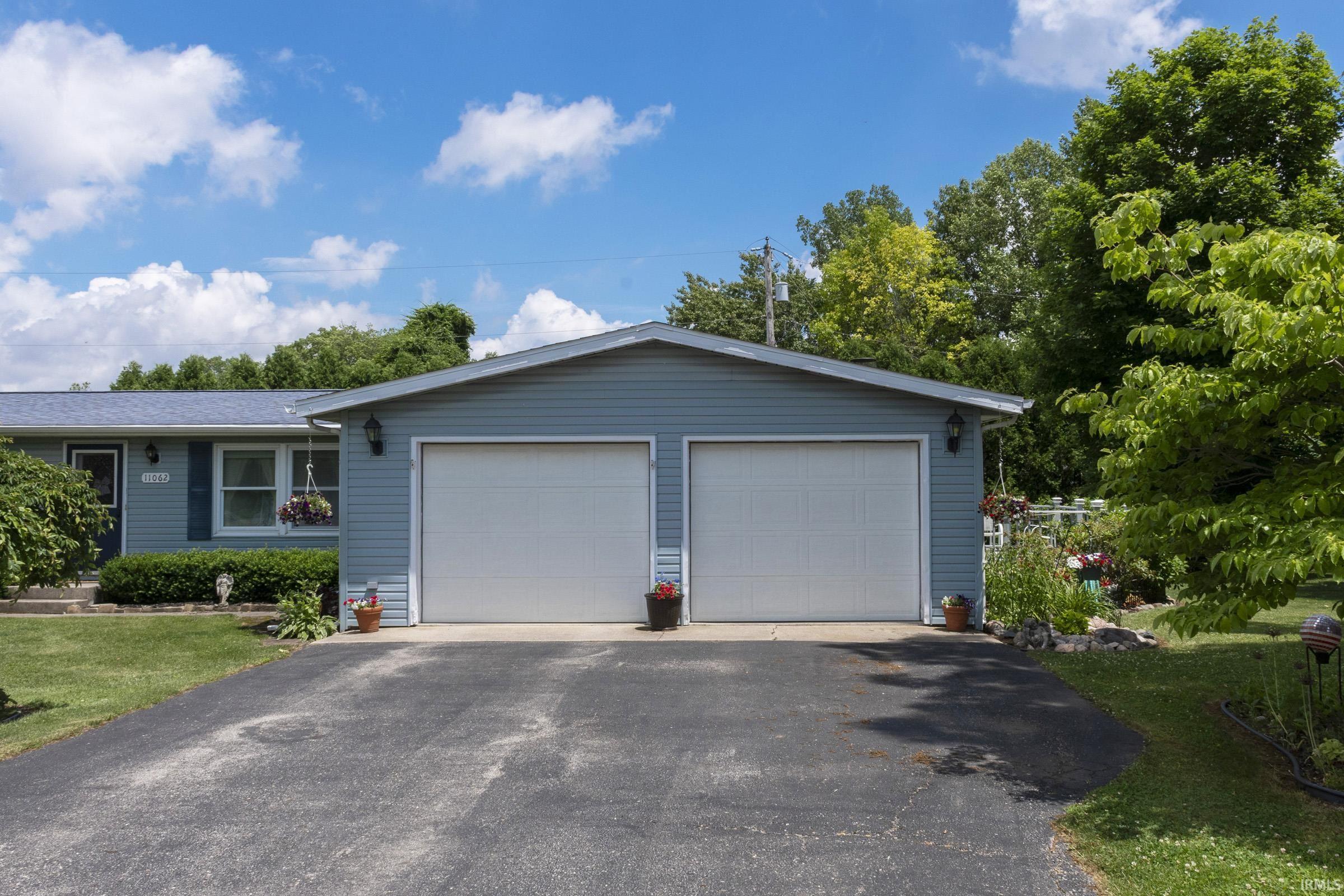 Exterior featuring a two-car garage with white doors, blue vinyl siding, and a paved driveway