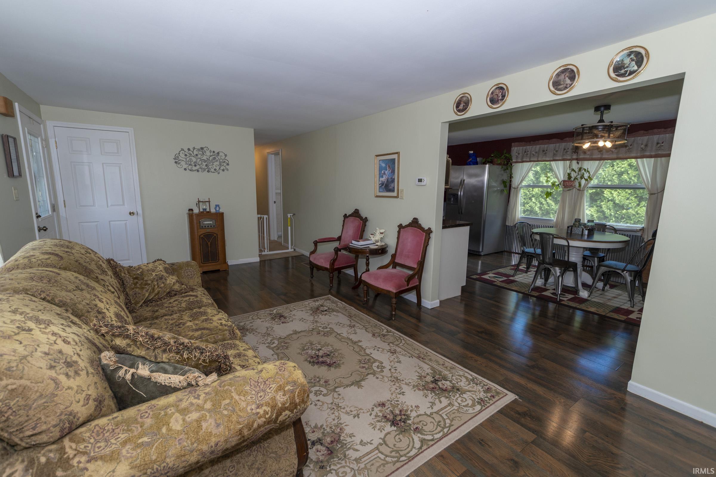 Open-concept living area featuring wood-finish flooring, light-toned walls, and white trim