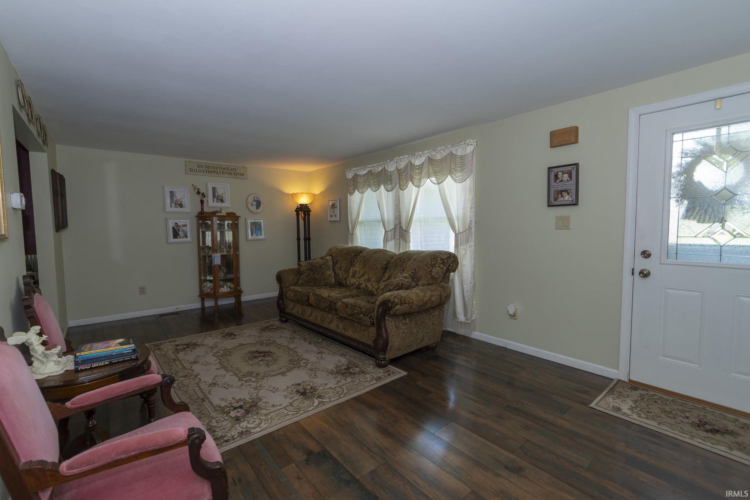 Spacious interior room featuring wood-finish flooring, light-toned wall paint, and a front entry door with decorative glass inserts
