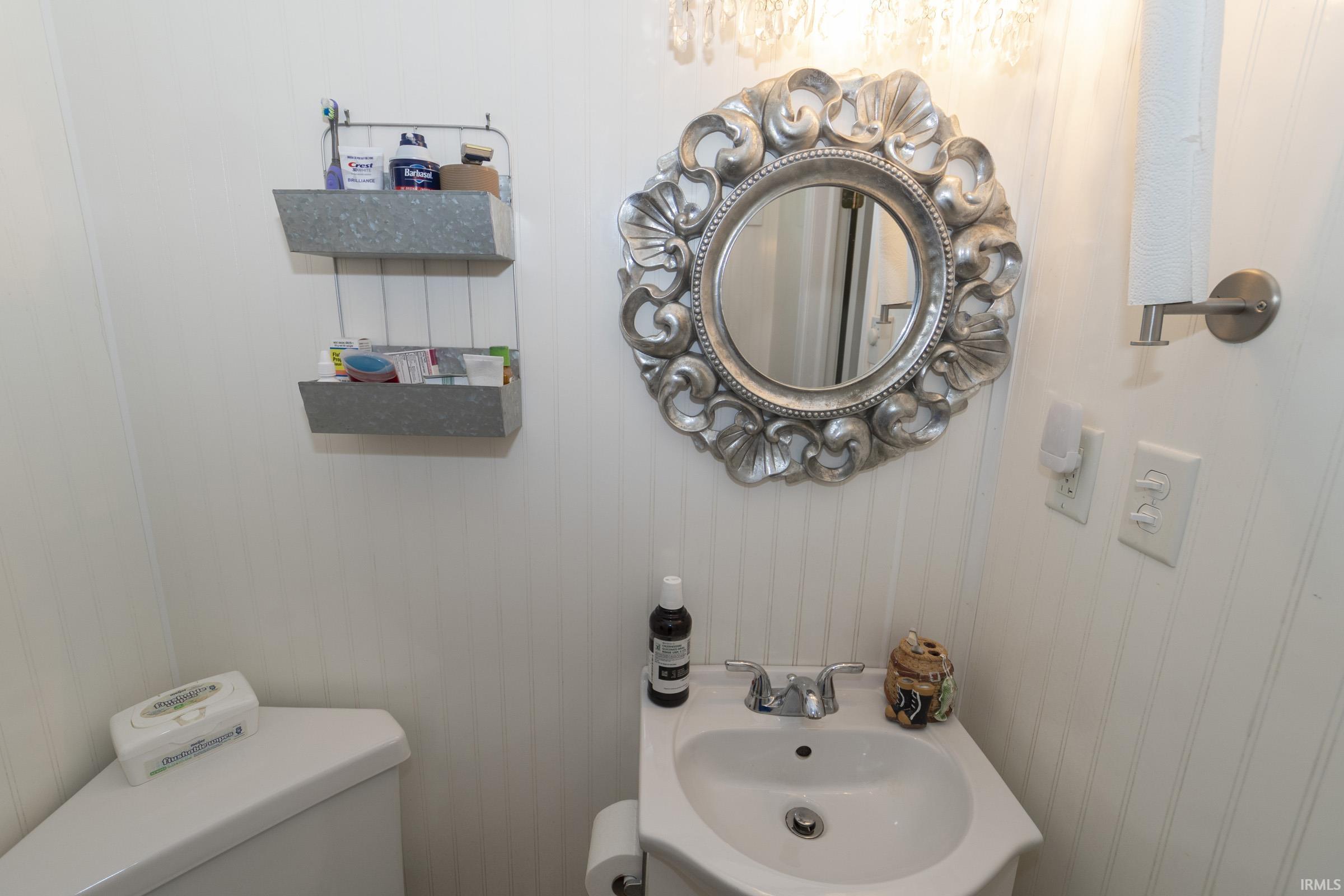 Pedestal sink with chrome-finish faucet, framed by a decorative mirror