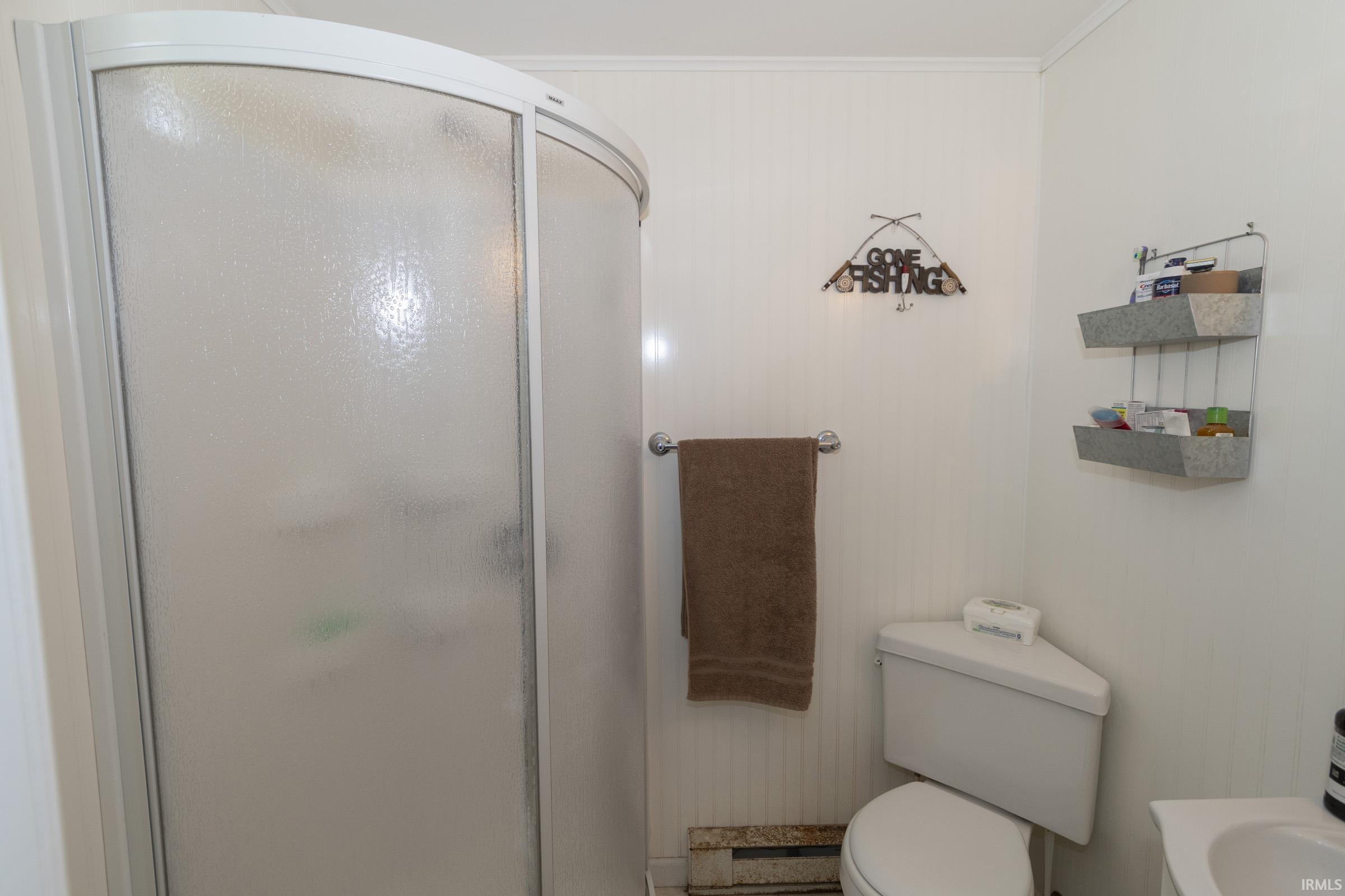 Enclosed shower with frosted glass panels, curved frame, and corner toilet with a white tank