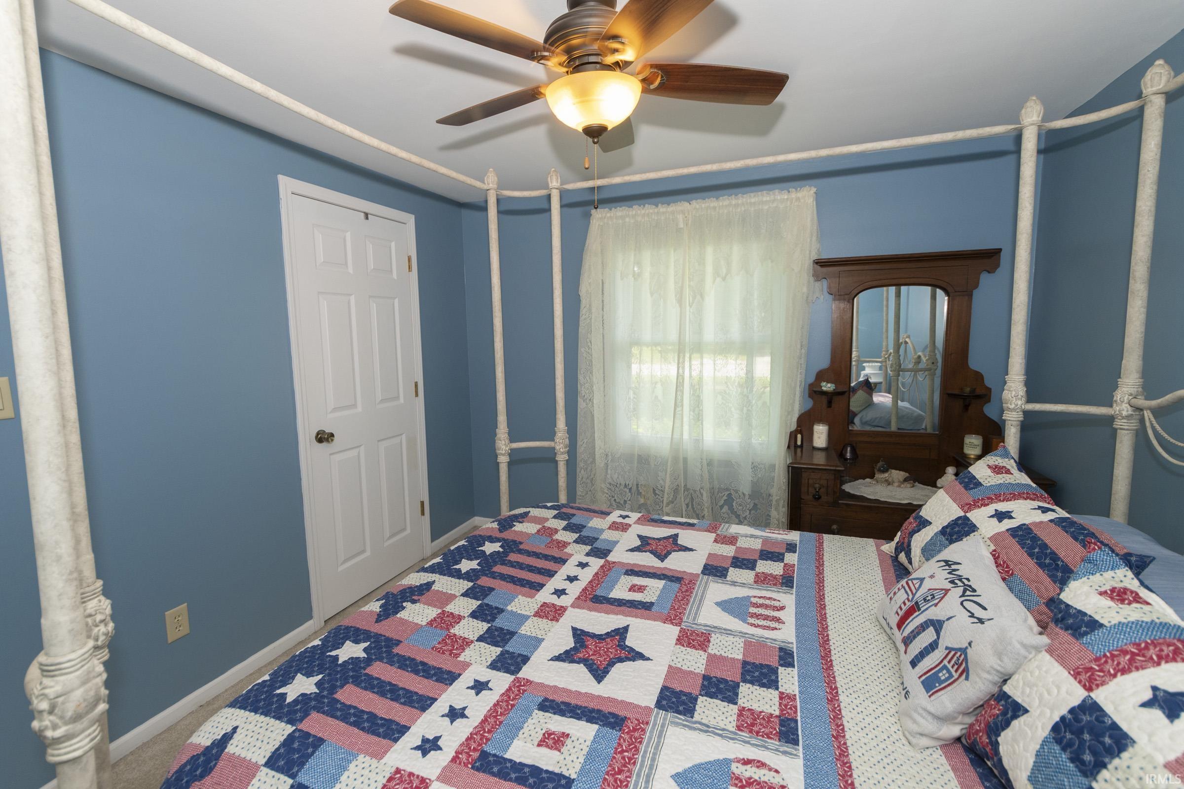 Bedroom featuring blue painted walls, a ceiling fan with light fixture, and carpet flooring