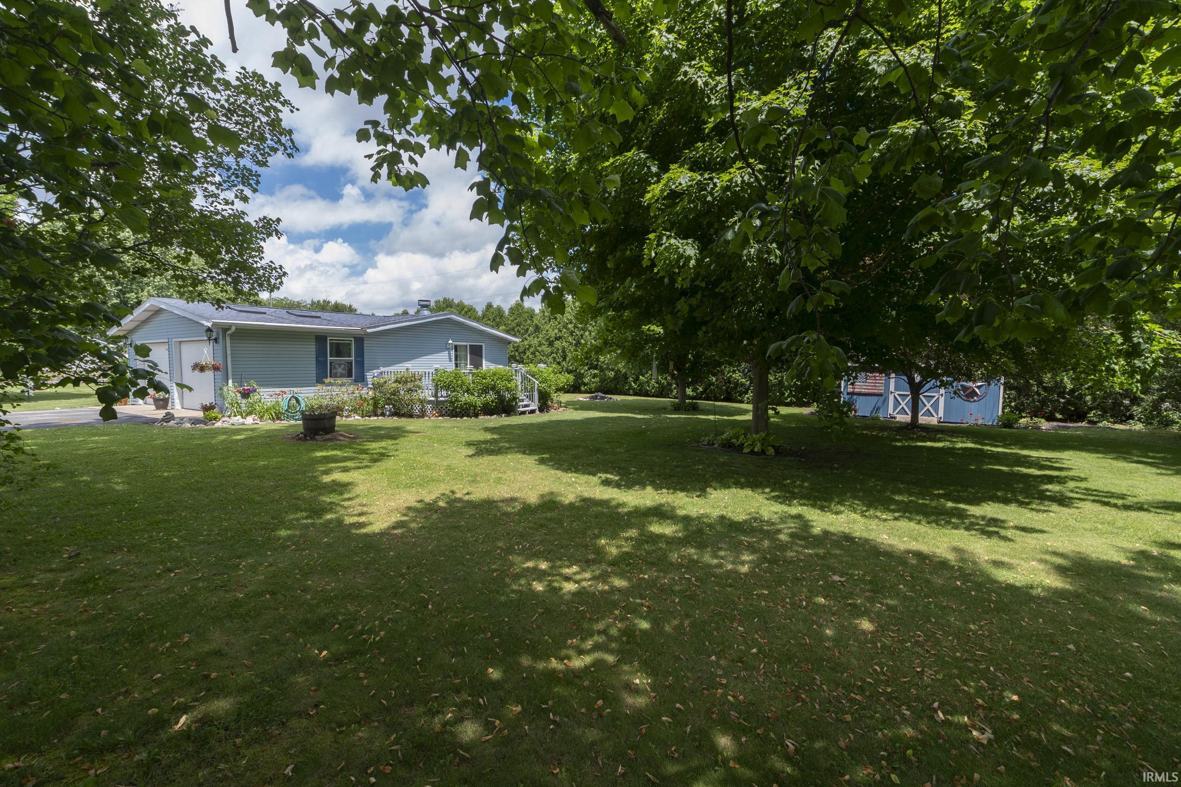 Expansive green lawn bordering a light blue residence with an attached two-car garage