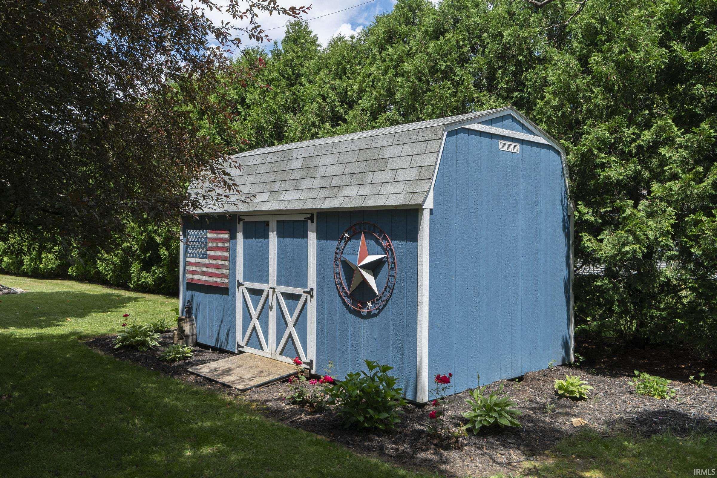 Blue gambrel-roof shed featuring white trim